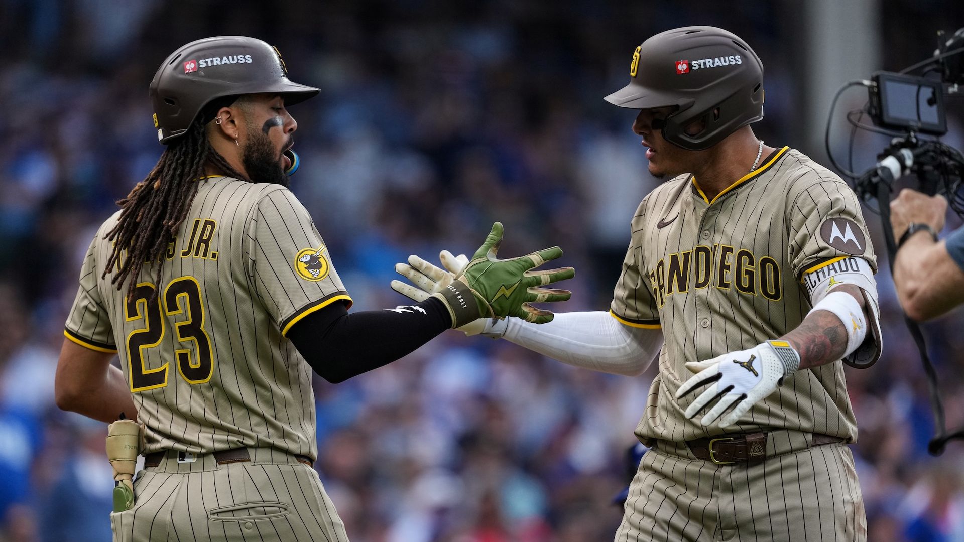 Fernando Tatis Jr. and Manny Machado high five in celebration after a home run. 