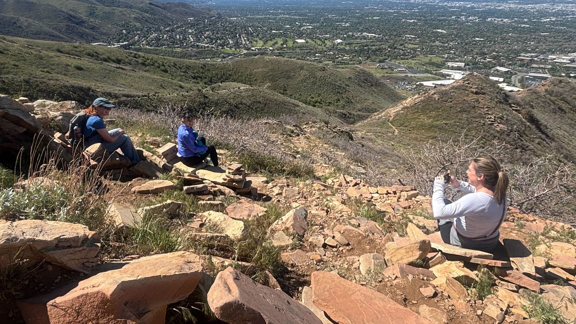 Three women sitting on rocks on top of a mountain