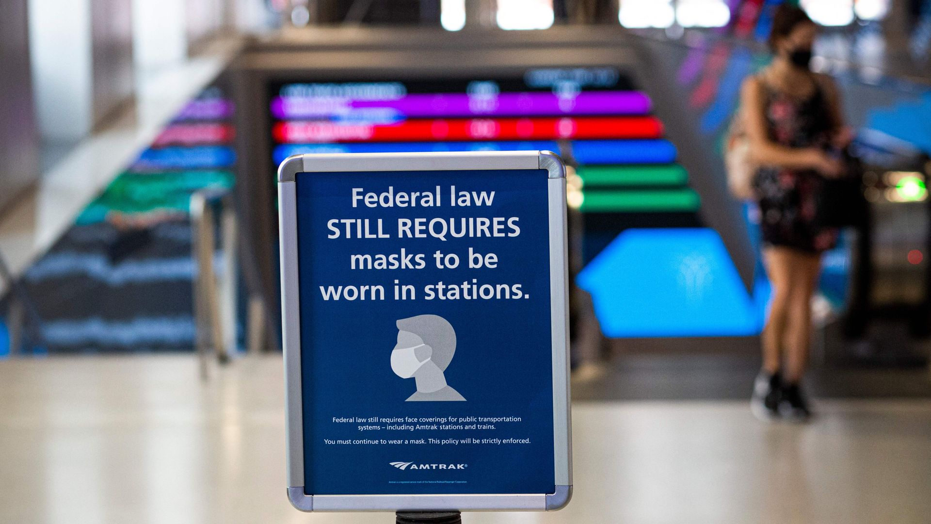 A woman walks past a sign calling for mask wearing at Penn station in New York on August 2, 2021.