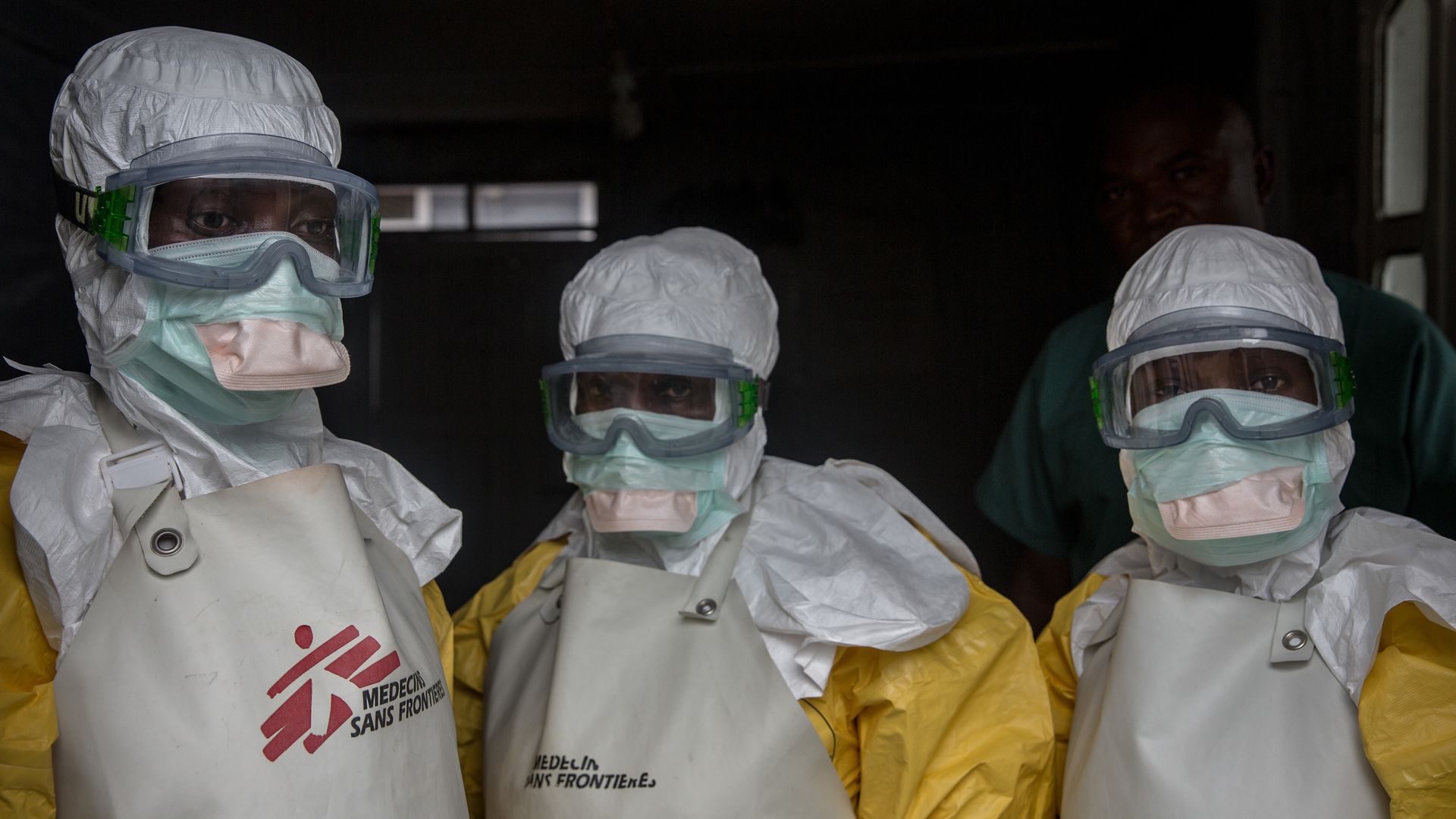 This image shows three people in protective medical gear that covers their faces and heads, and goggles.