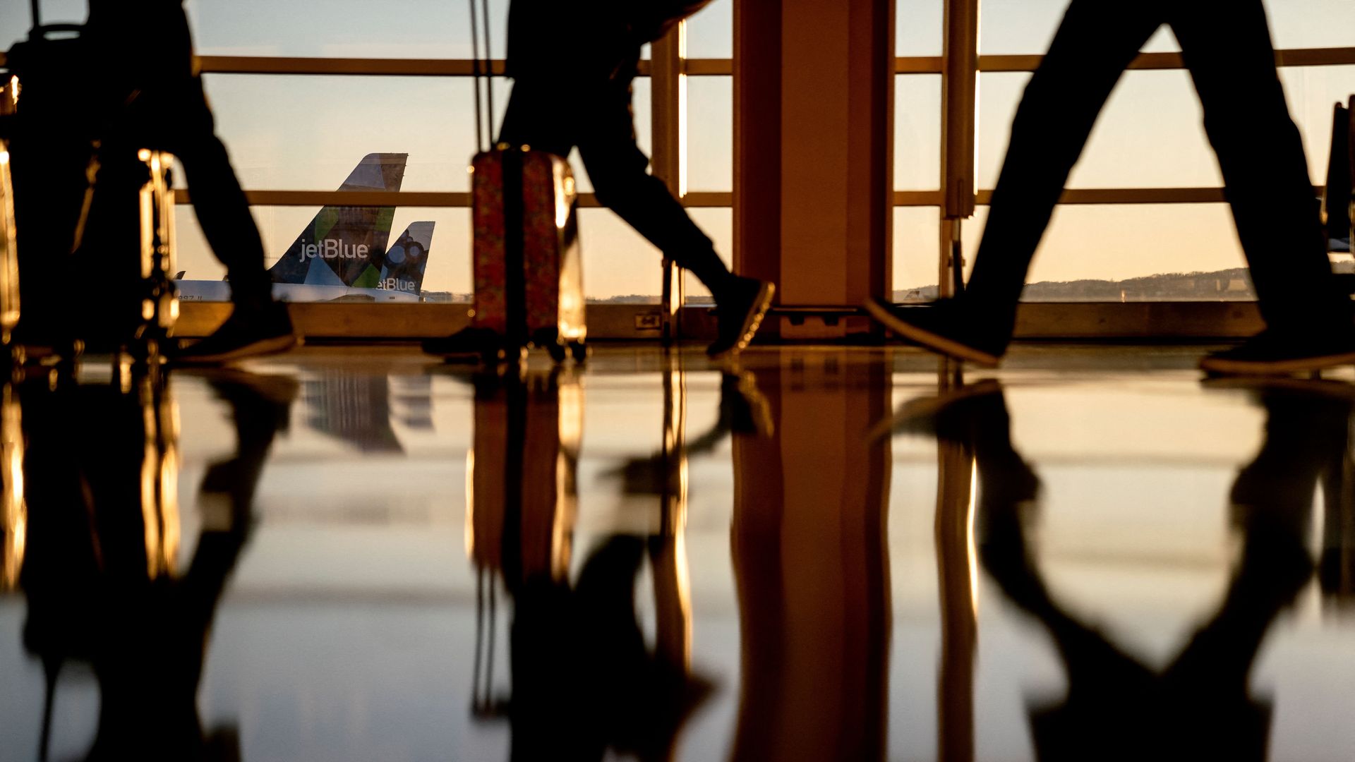 Air travelers walking inside National Airport against the backdrop of airplanes