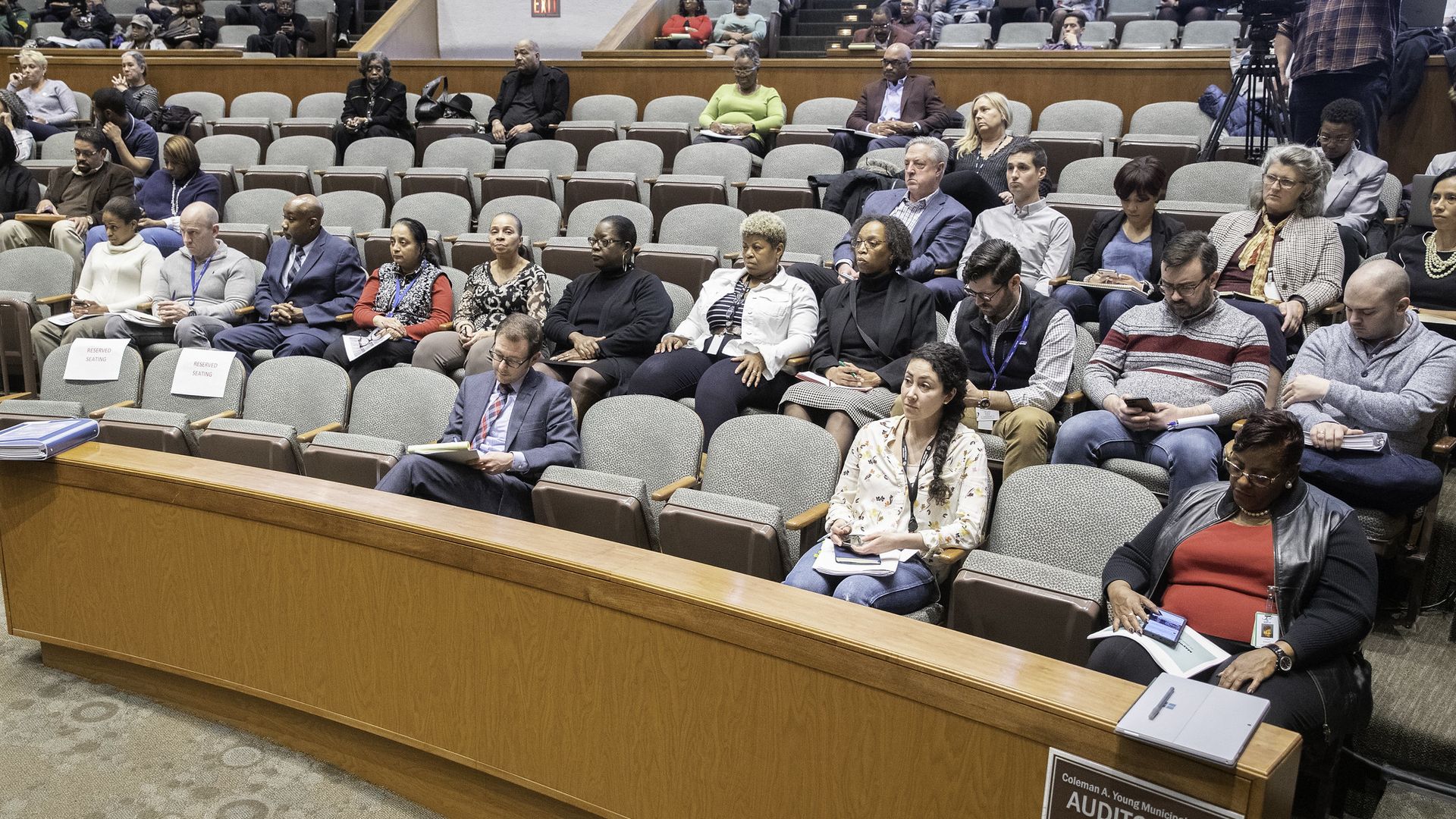 People are seated in a large auditorium. 