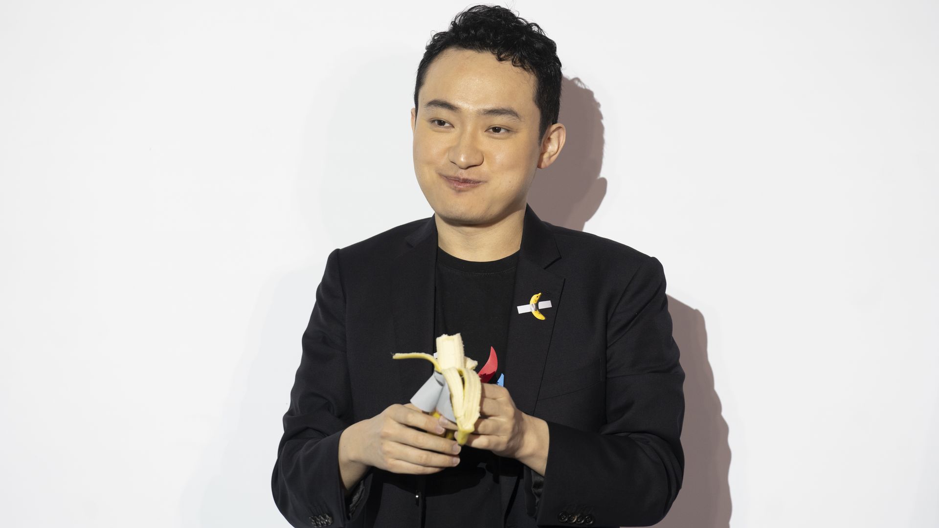 A man in a sports jacket eating a banana