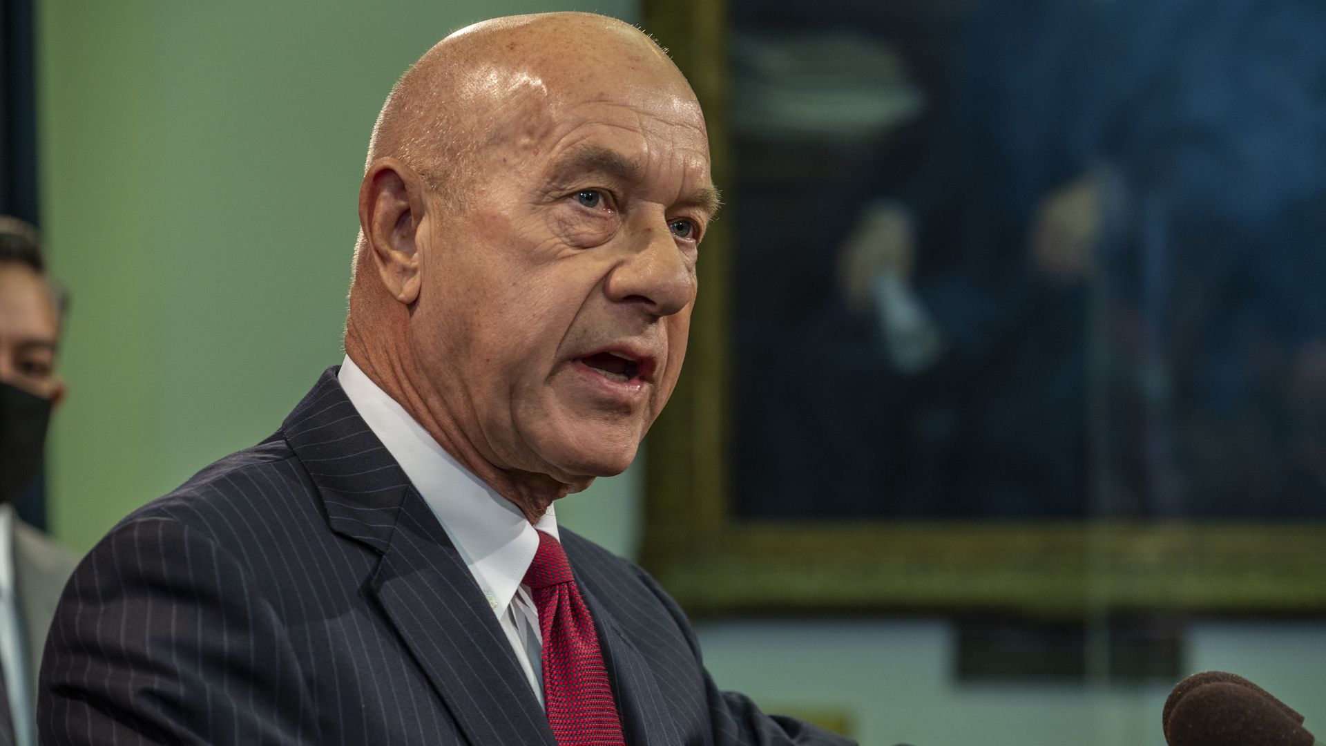 Photo of a white, bald man with a red tie. 