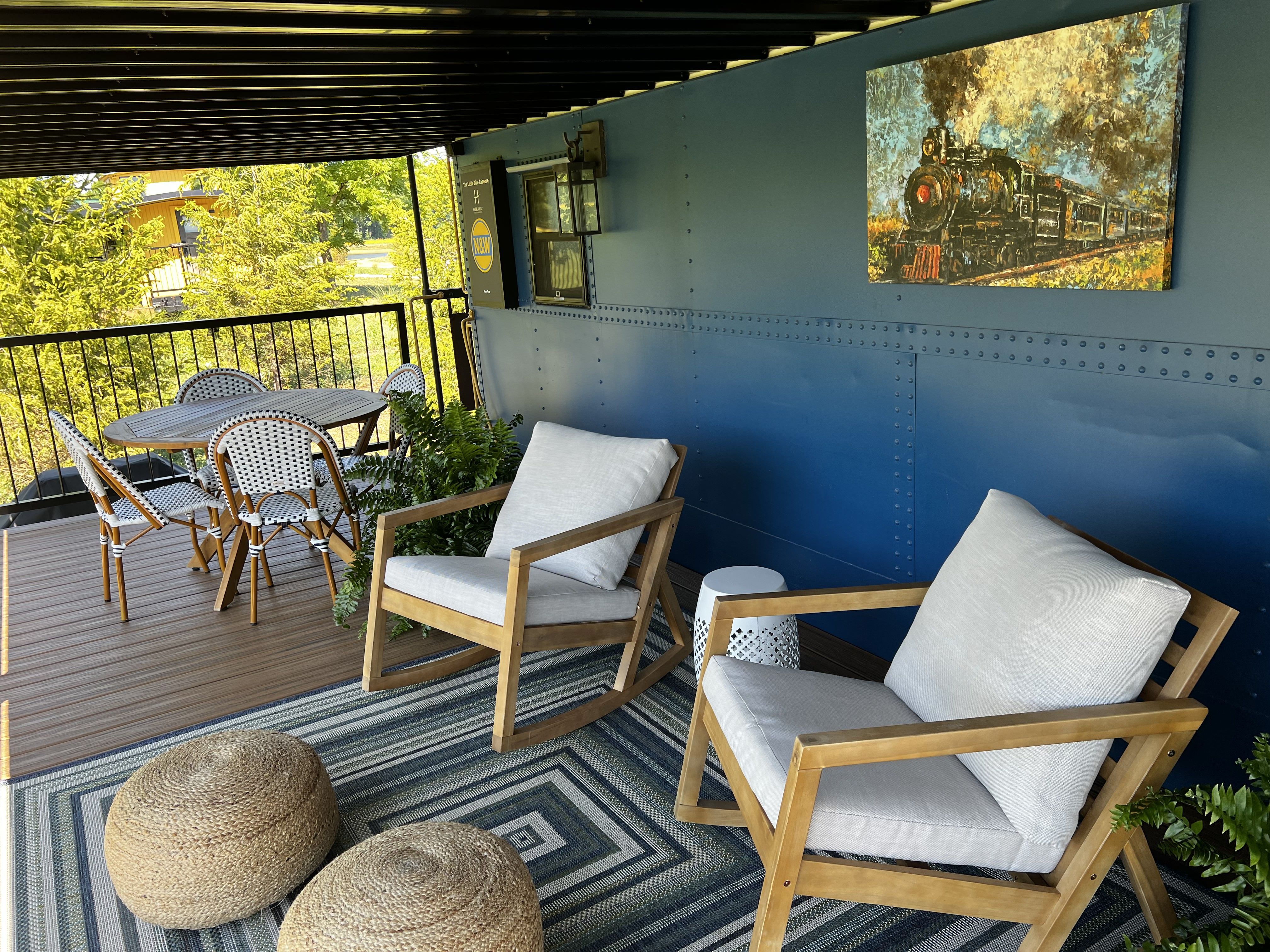 The porch of a blue cabin with chairs. 