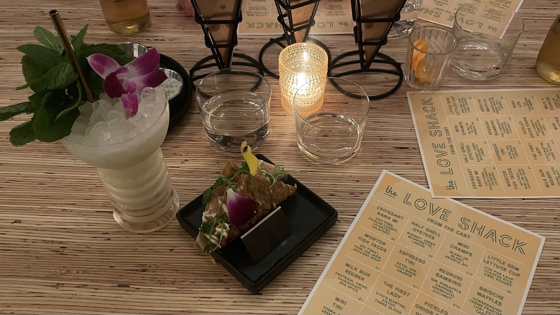 A photo of a table with a drink and a bingo-card menu that says "The Love Shack"