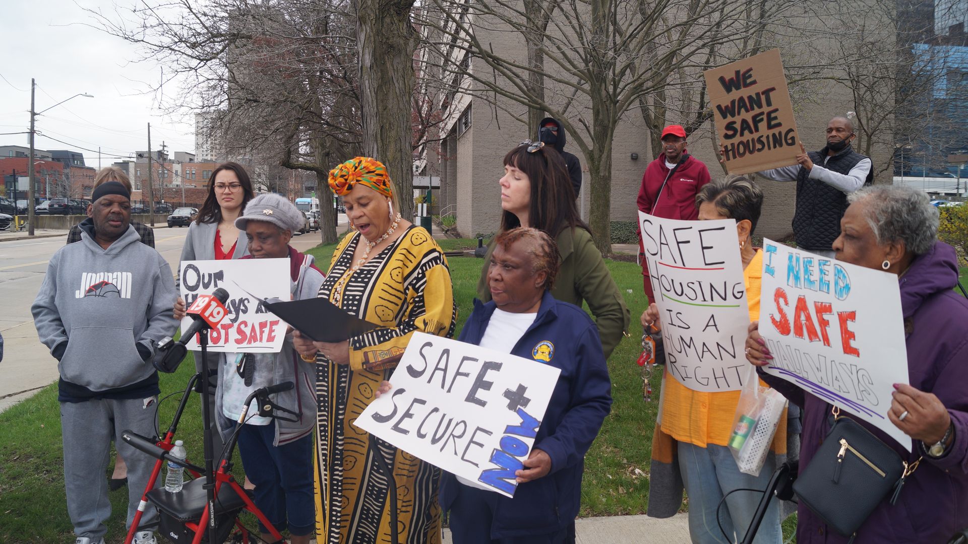 A picture of a group of residents with signs protesting outside their apartment building 