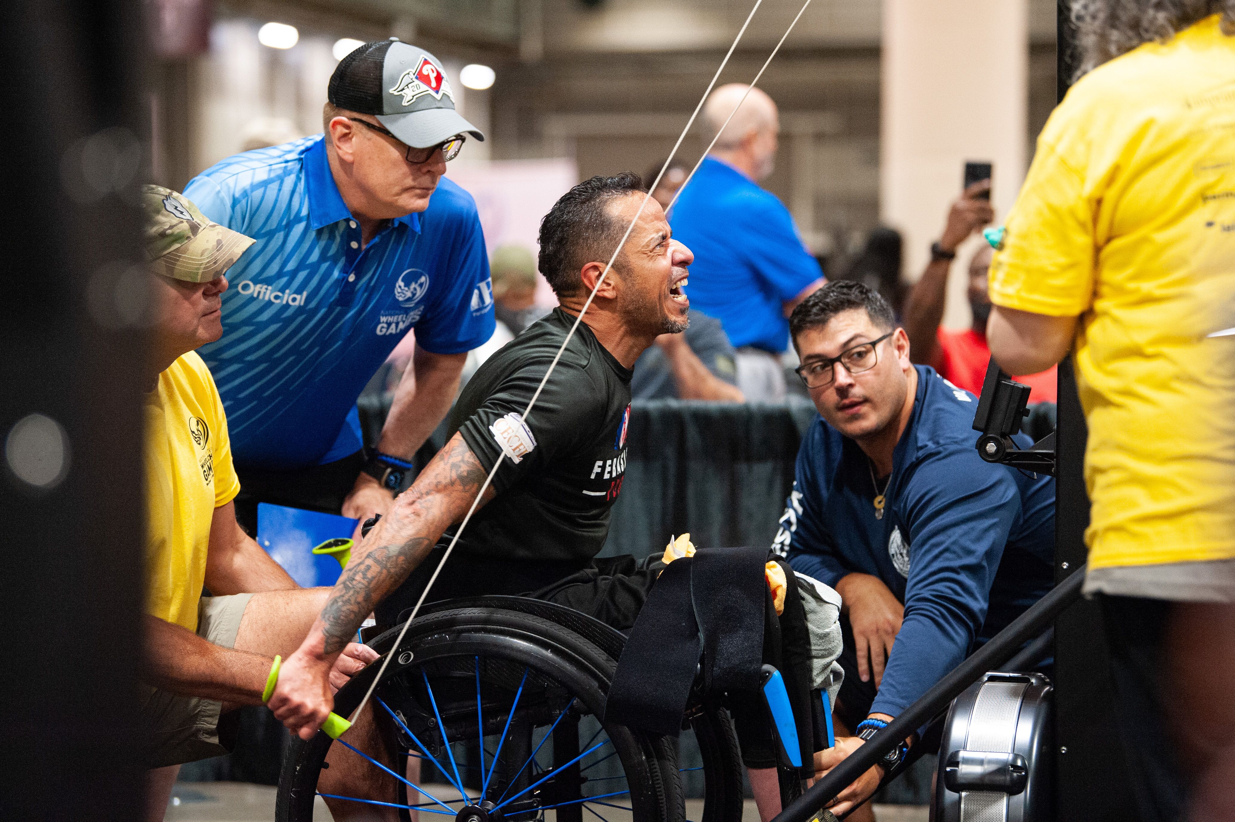 An athlete in a wheelchair pulls on cables to lift weights.