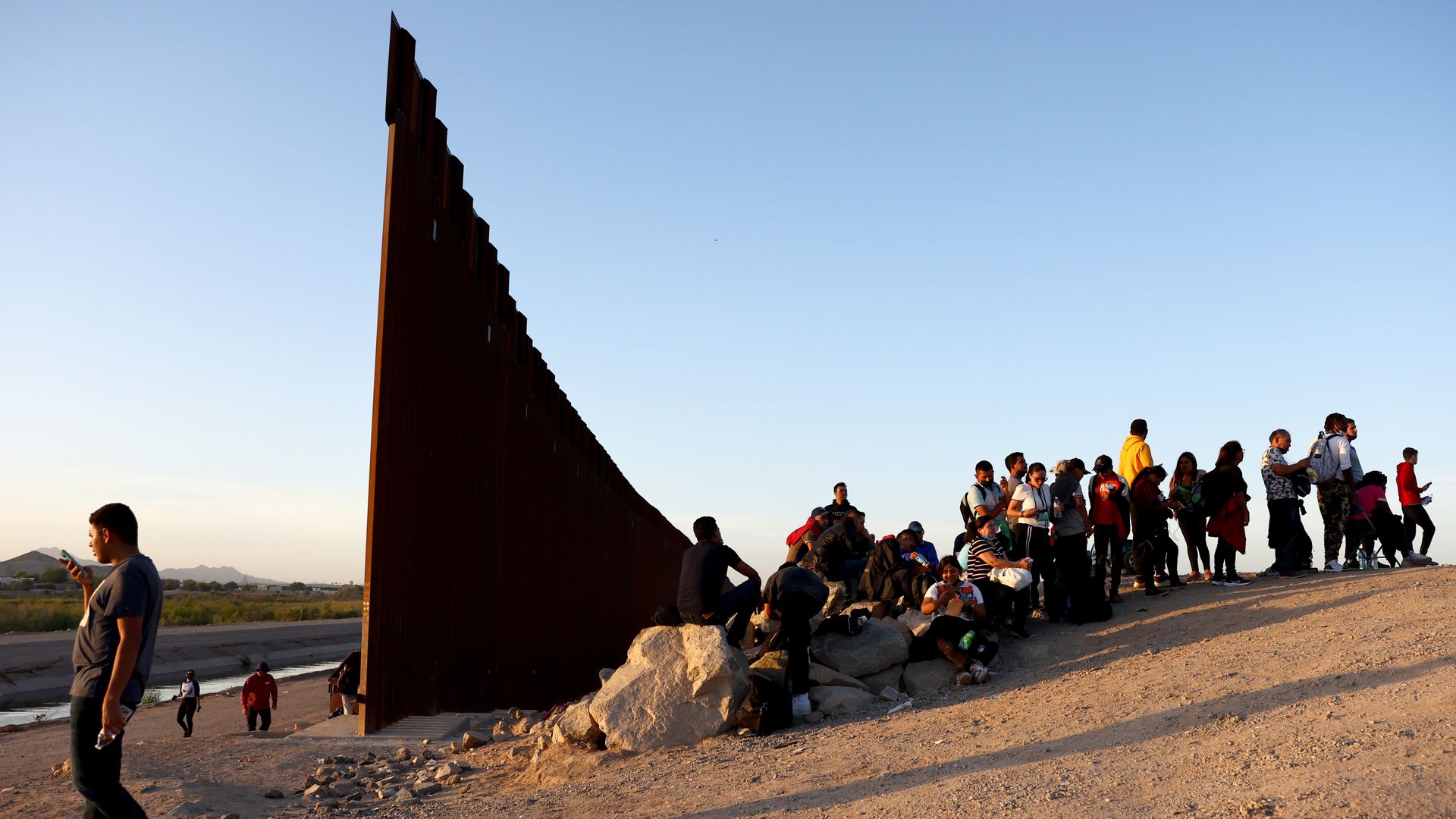  Immigrants wait to be processed by the U.S. Border Patrol after crossing through a gap in the U.S.-Mexico border barrier 