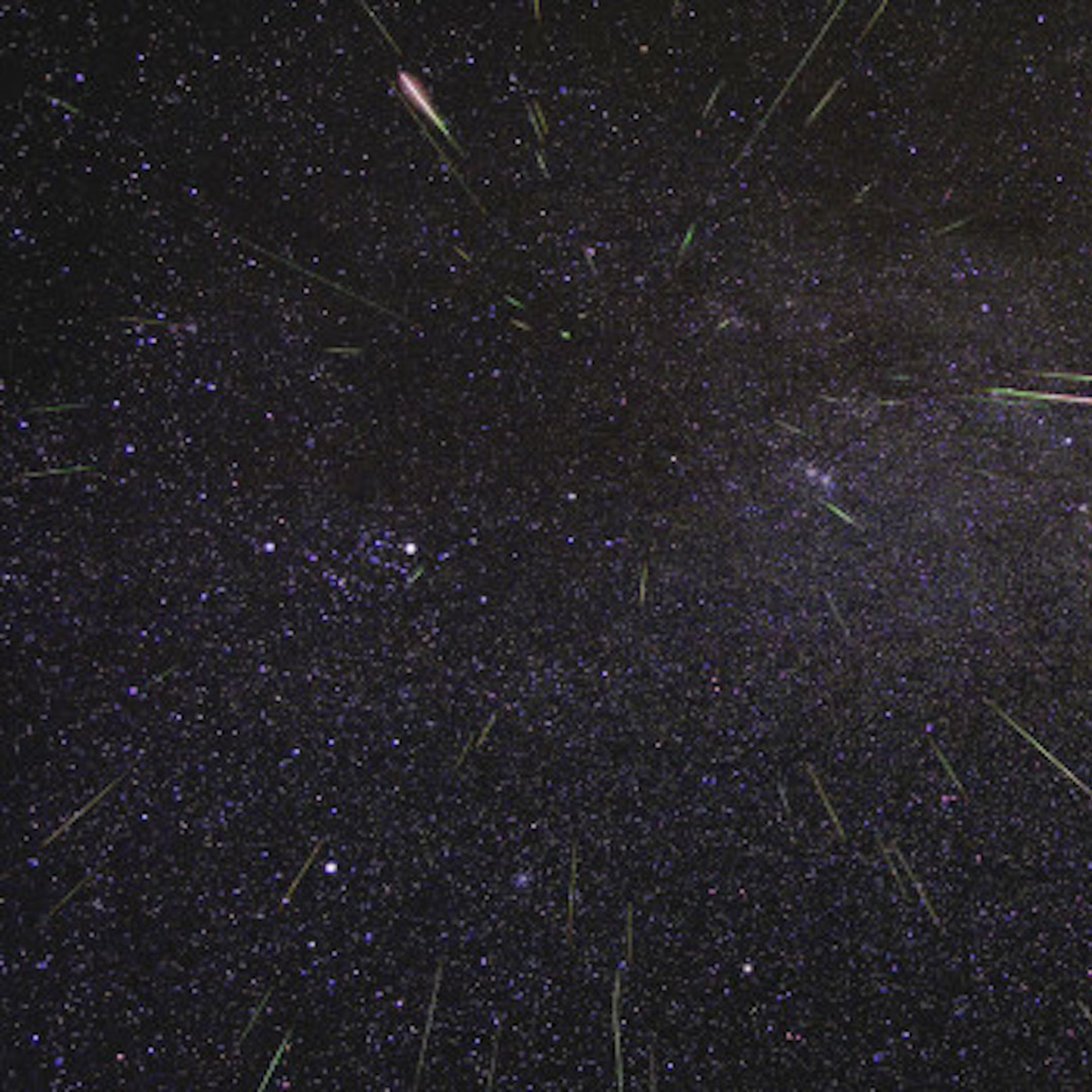 Streaks of meteors streaming in a dark, star-dotted sky.