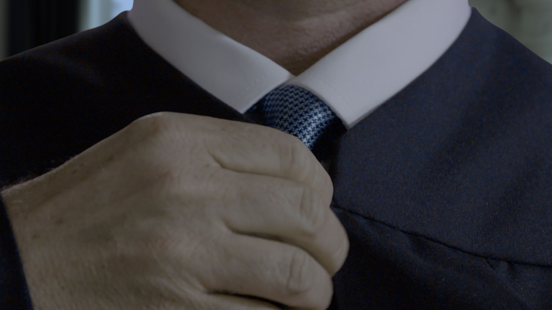 An image of a hand fixing a tie.