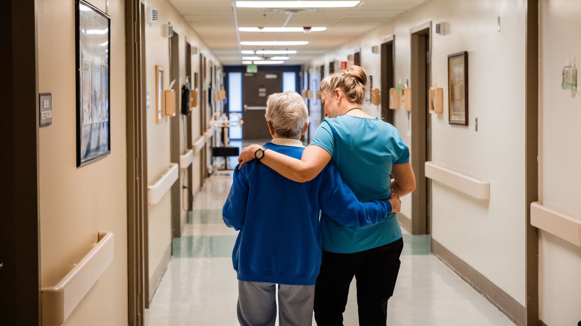 Jen Lingo, R.N., walks a resident of the assisted living center in Dayton General Hospital back to her room.