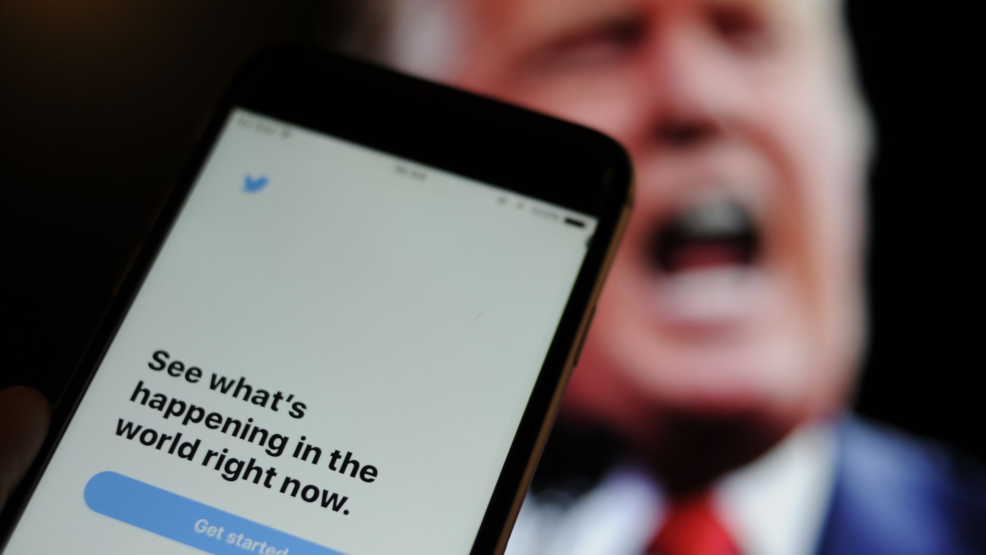 The Twitter app is seen with an image of US president Donald Trump in the background.