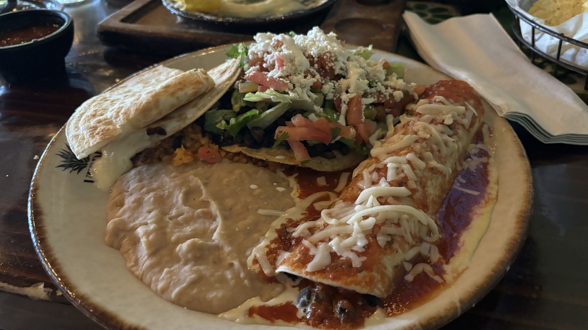 A plate of food with an enchilda and beans