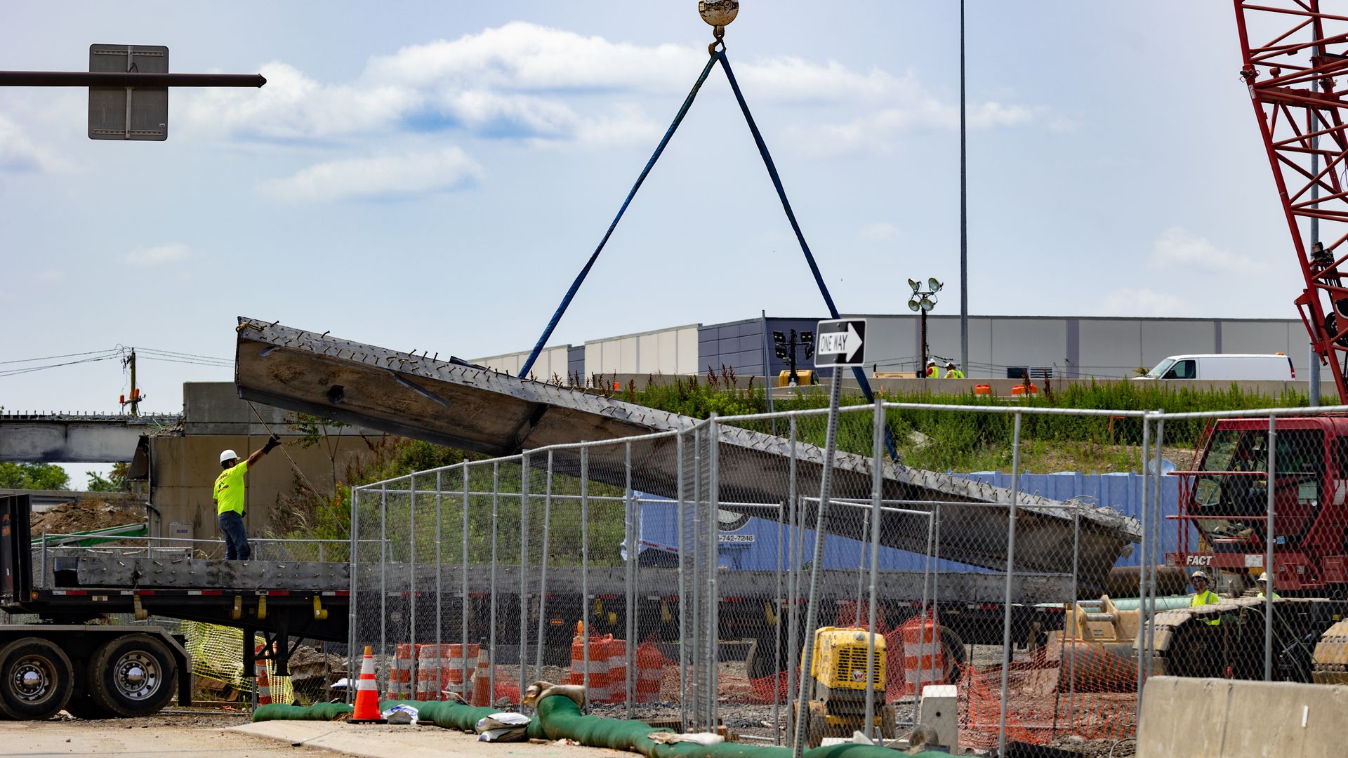 A worker directs a crane moving debris from I-95.