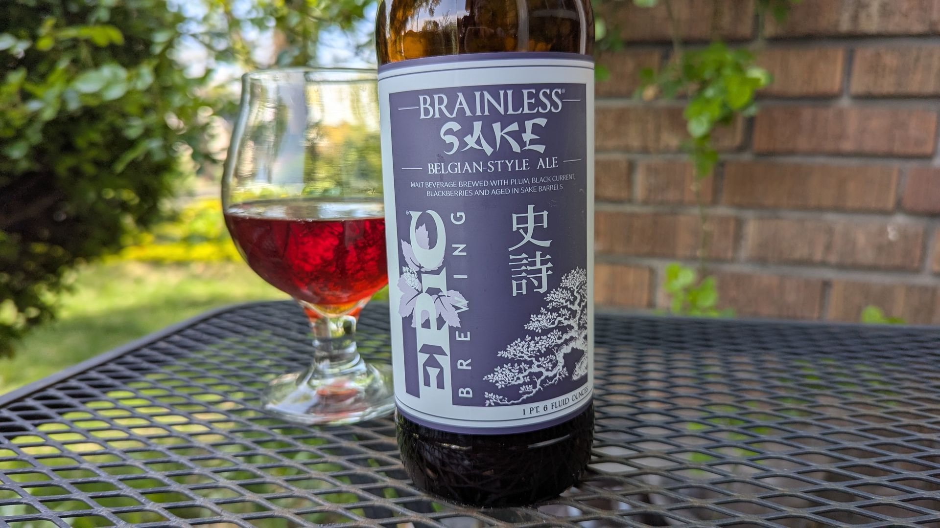 A bottle of beer labeled "Brainless Sake" in front of a small glass with beer inside.