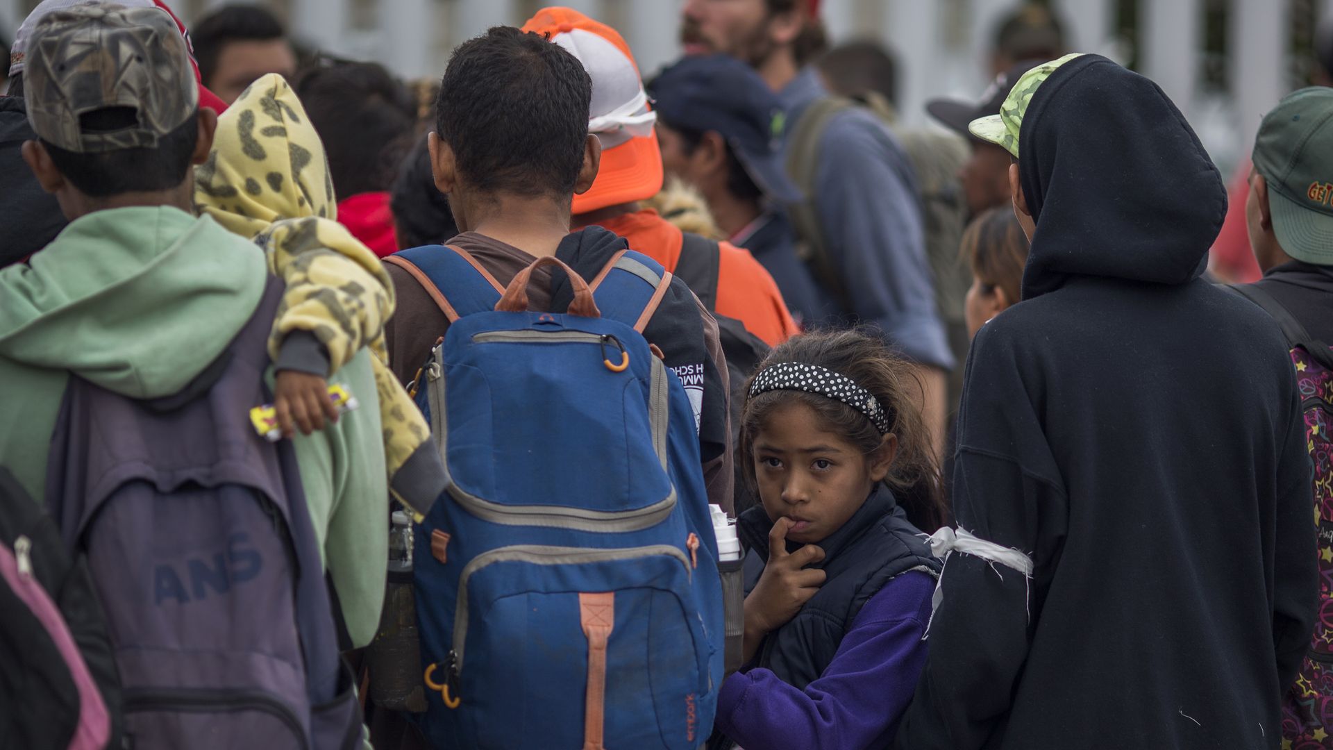 Members of Central American caravan. One young girl looks back with her finger in her mouth