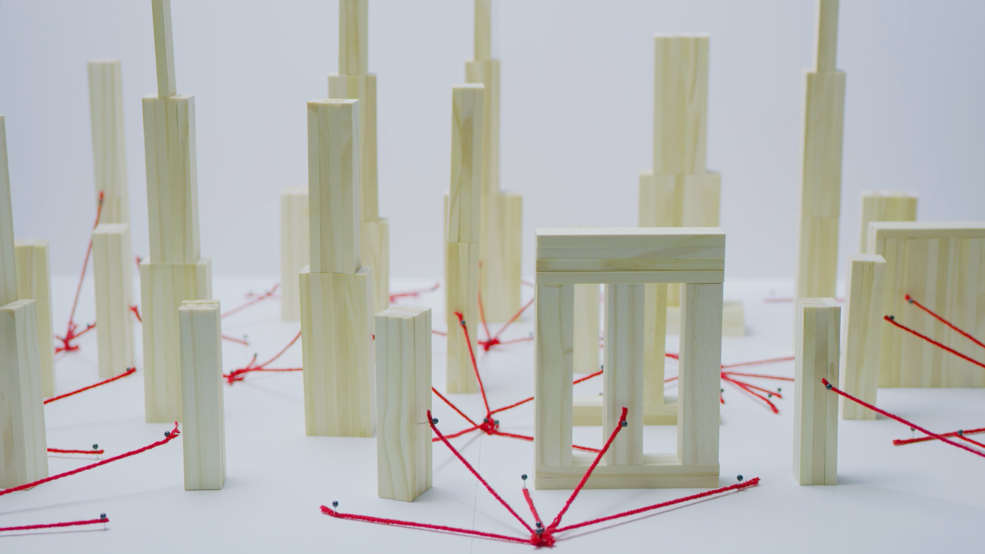 City made out of wooden blocks with red yarn radiating to the buildings depicting 5G wireless signals