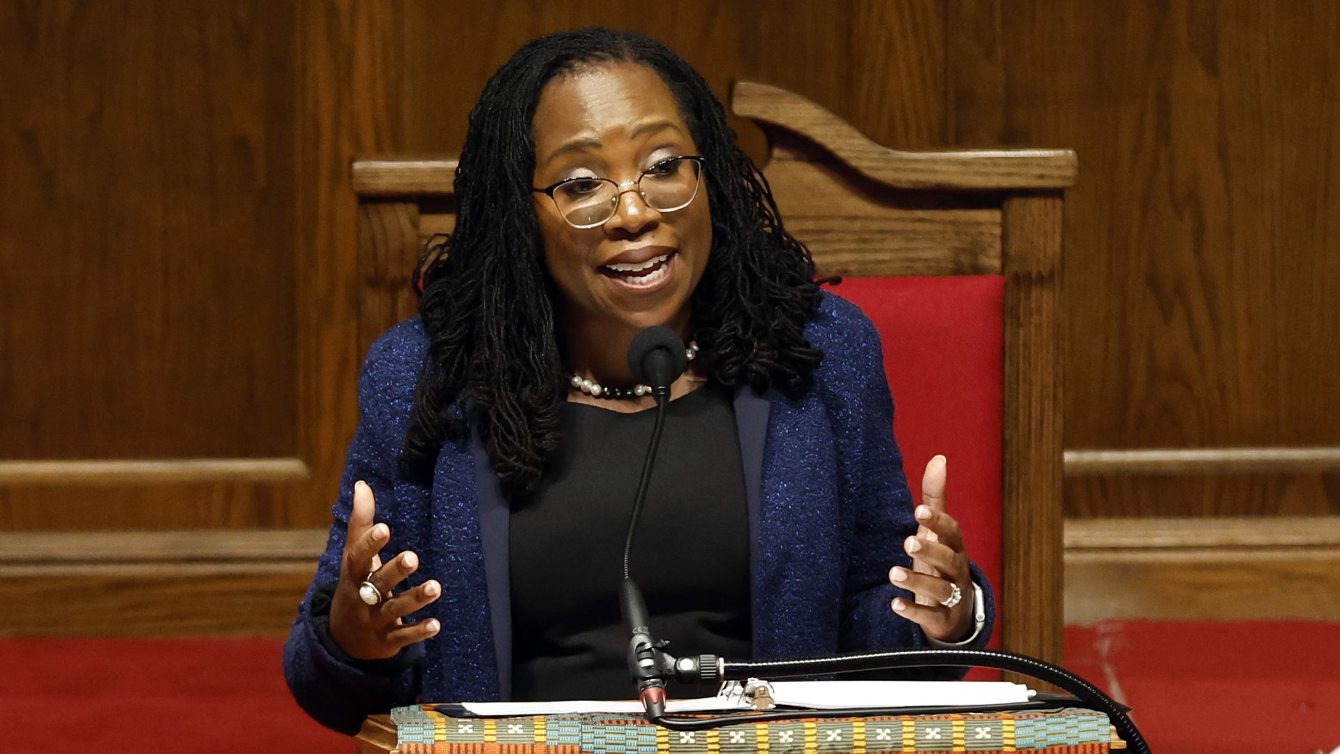 Ketanji Brown Jackson sits on a red chair and speaks into a microphone 