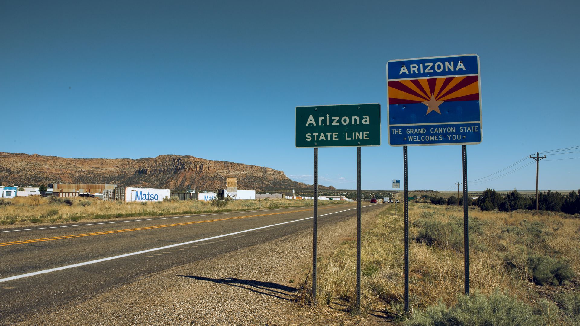 A road with signs that say, "Arizona State Line."