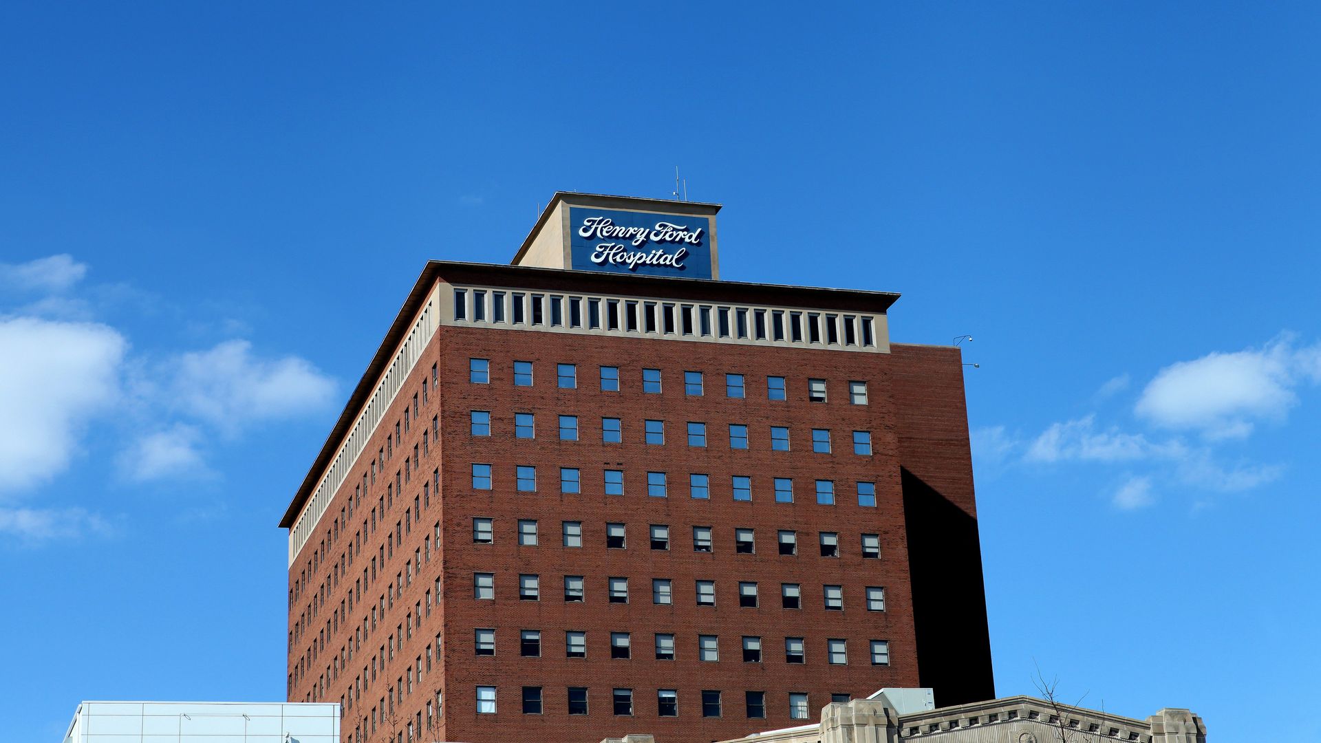 A shot of the tallest tower of Henry Ford Hospital, all red brick with the hospital's logo on it.