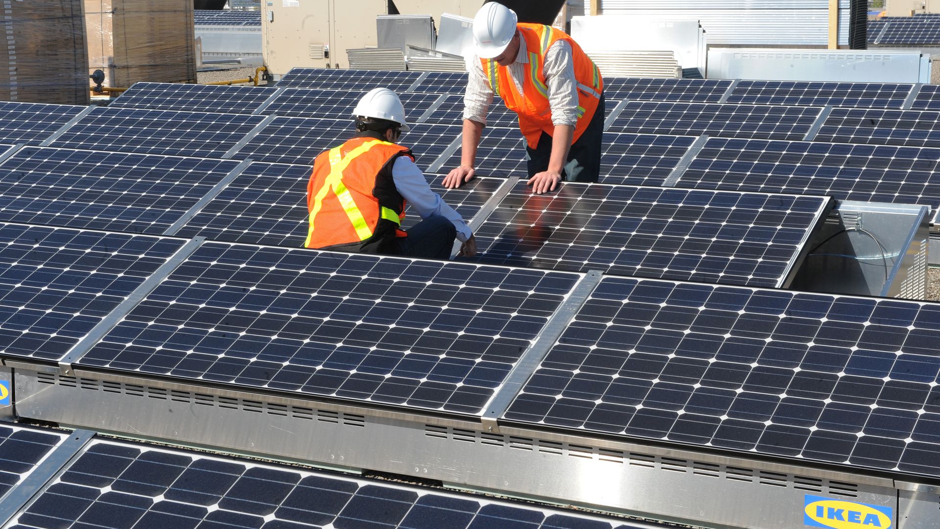 Workers install solar panels on the roof of an Ikea