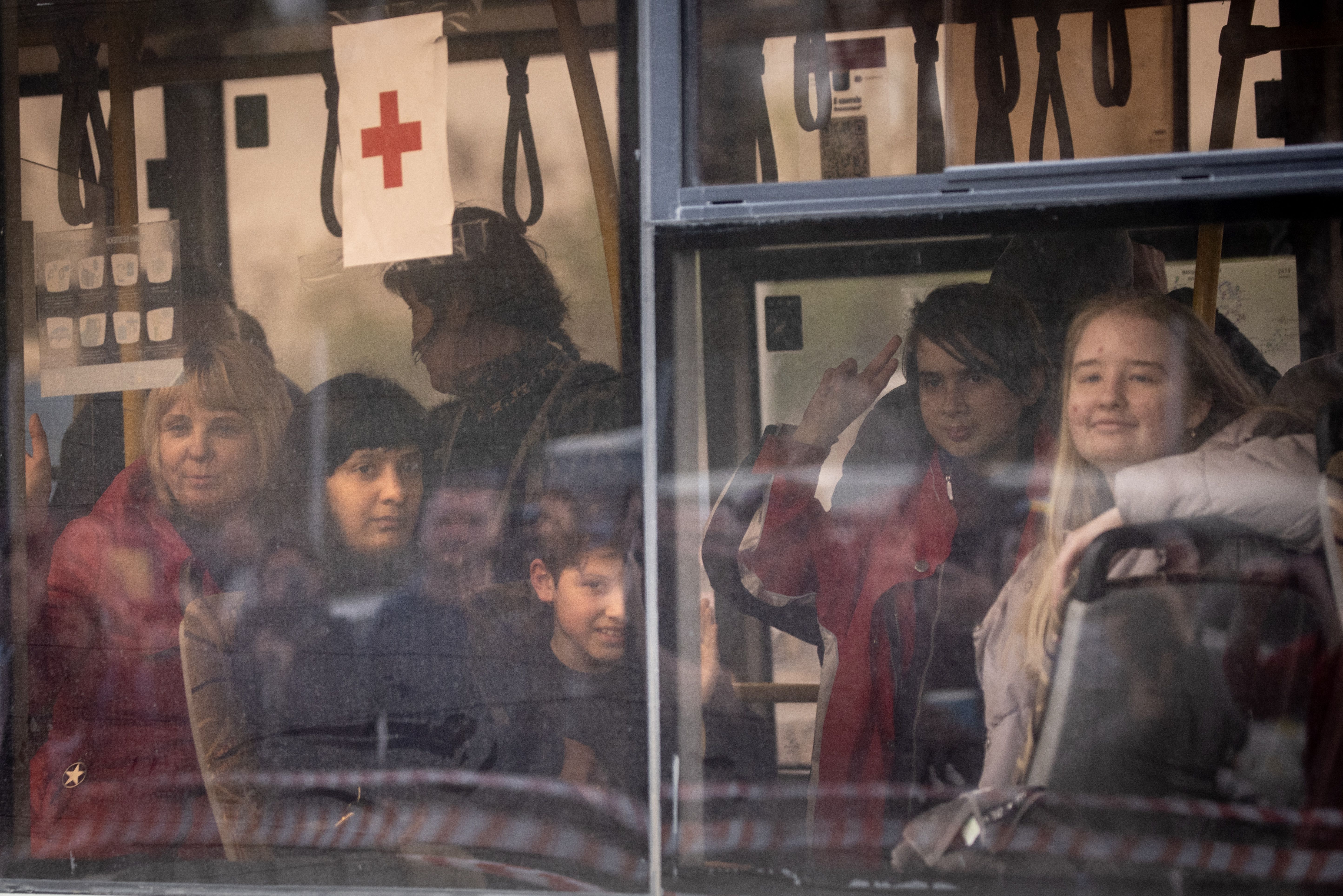 Evacuees including some from the Azovstal plant wave as they arrive on a bus at an evacuation point for people fleeing the Azovstal plant, Mariupol,
