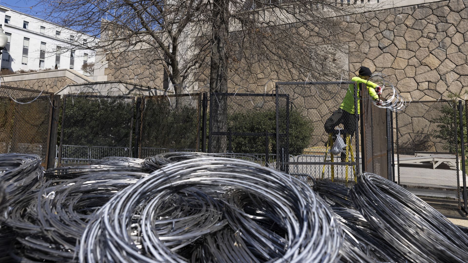 A worker is seen dismanting the barbed wire that had been placed atop extra fencing around the Capitol complex.