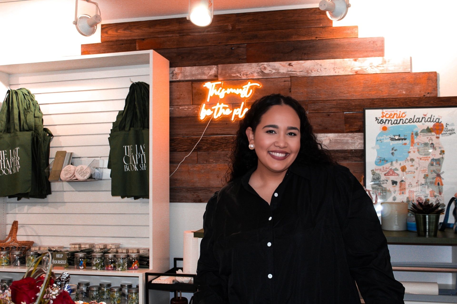 Woman standing in front of tote bags and a print in a frame.