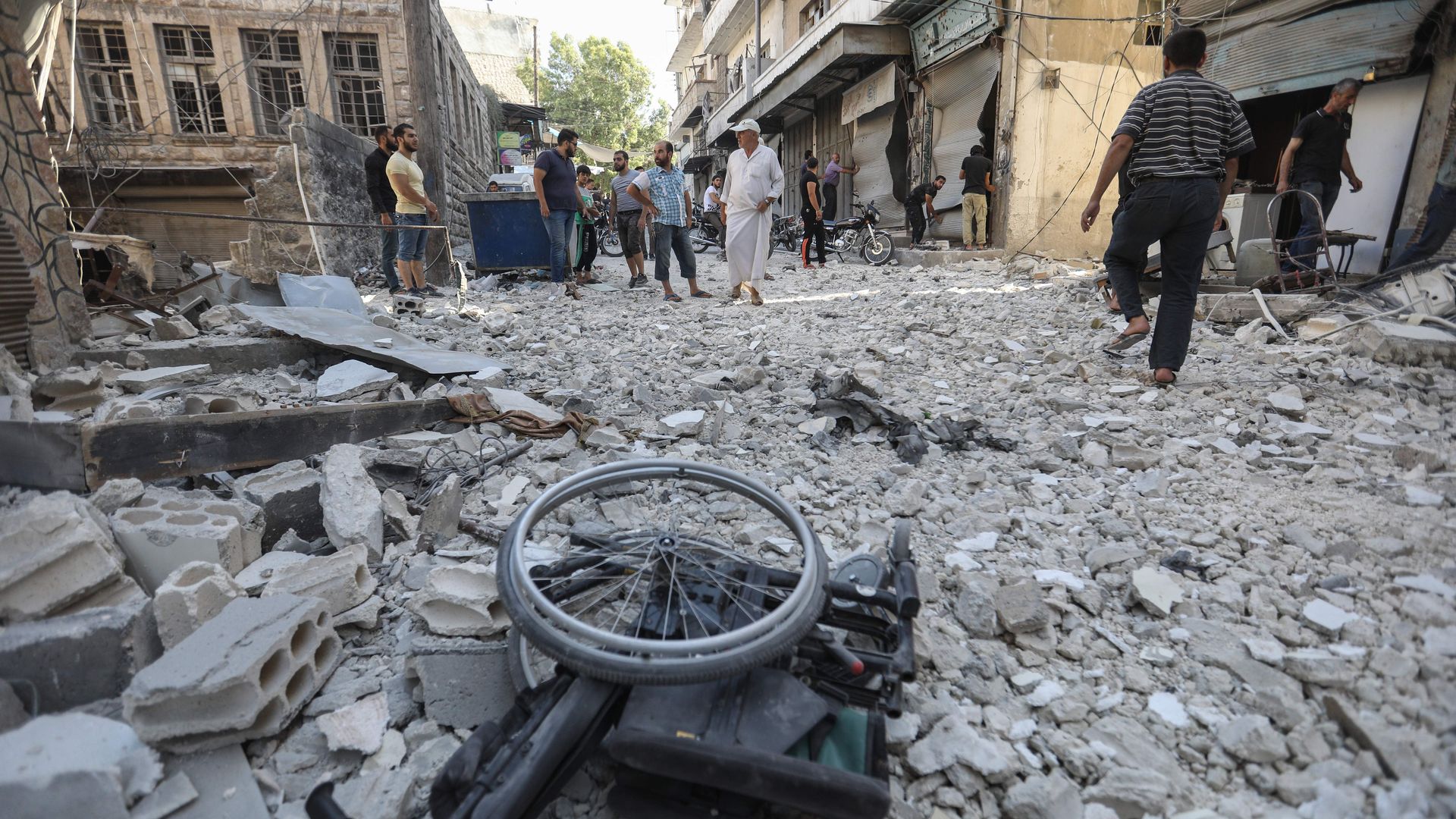 rubble of a building hit by an airstrike, with people standing in the background