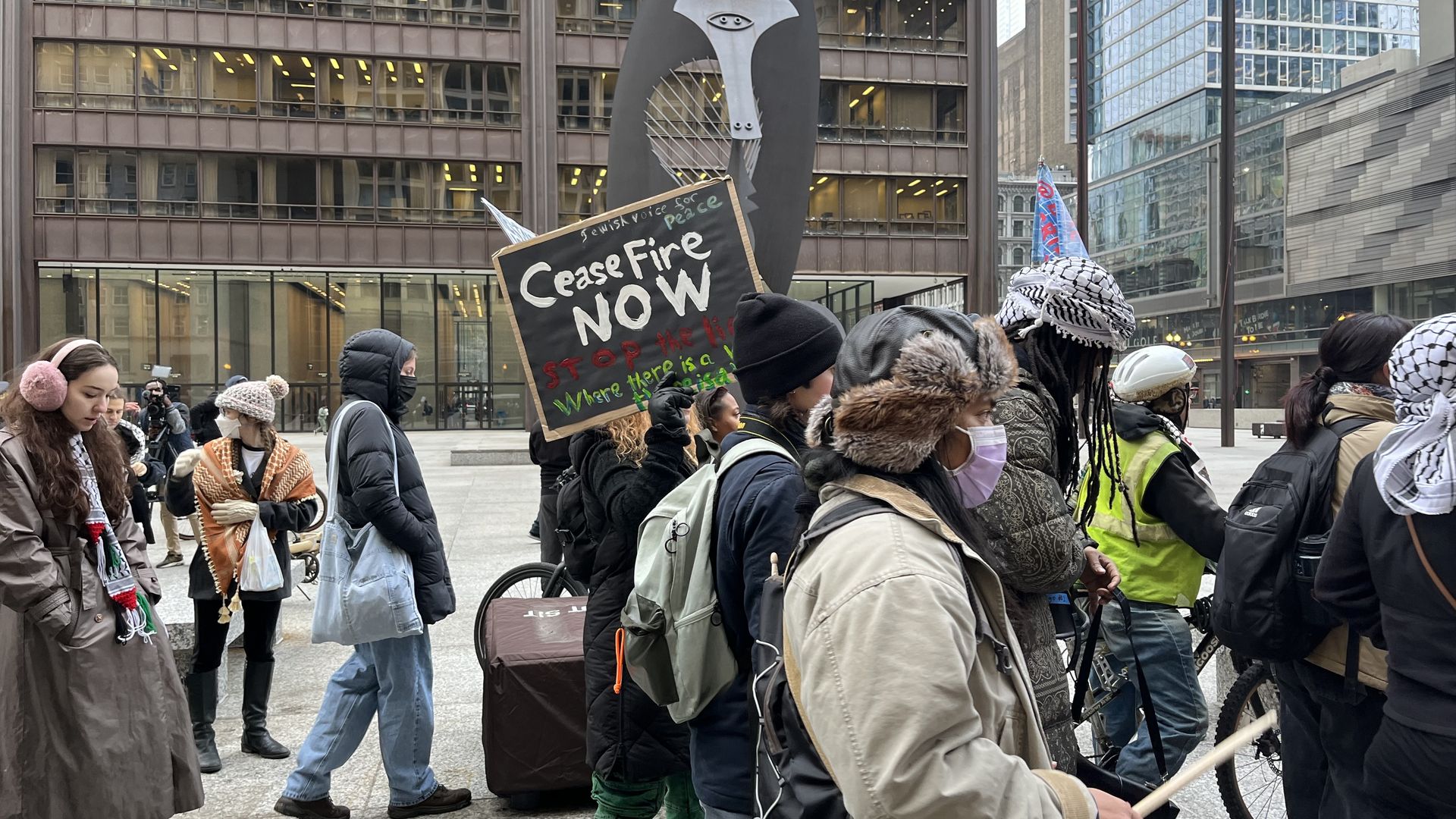Protesters march in downtown Chicago, with a "Ceasefire now" sign.