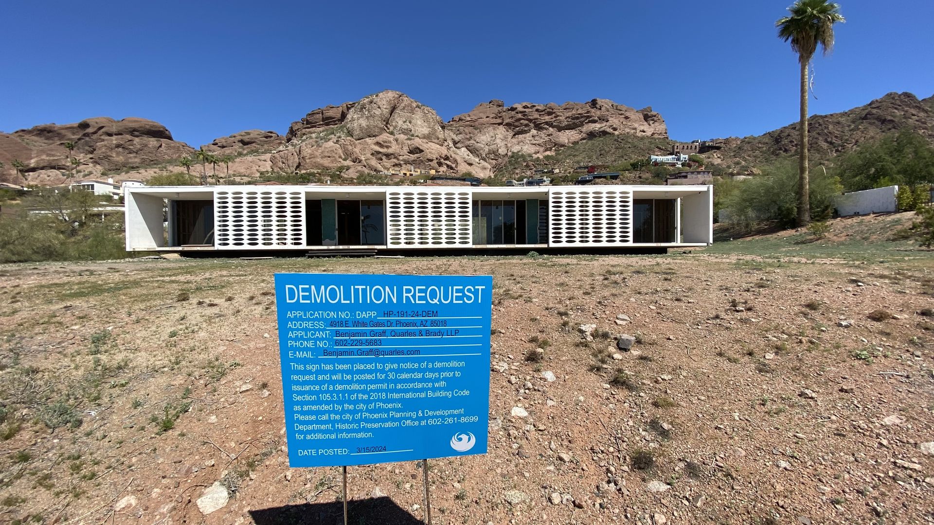 A sign that says, "Demolition Request" outside of a mid-century modern building.