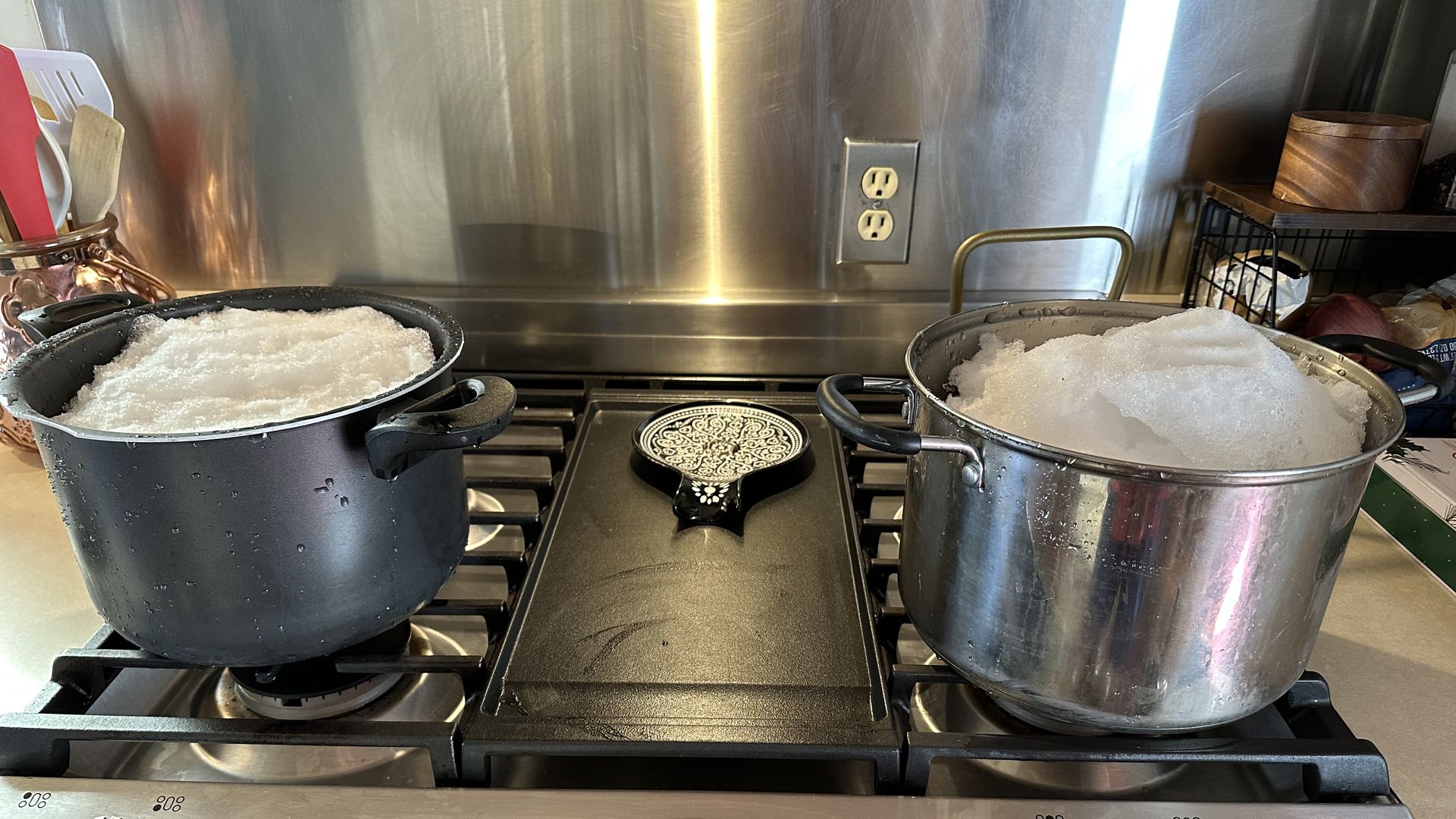 two pots of snow on a stove 