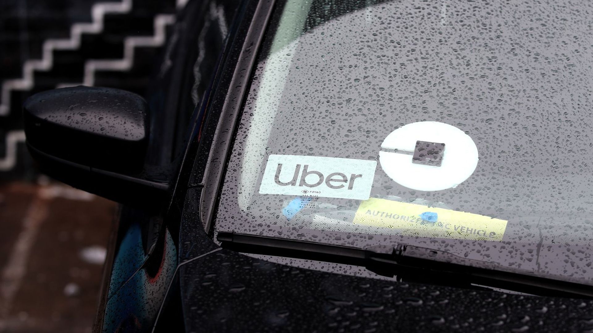The rain-dripped windshield of a car being used for Uber