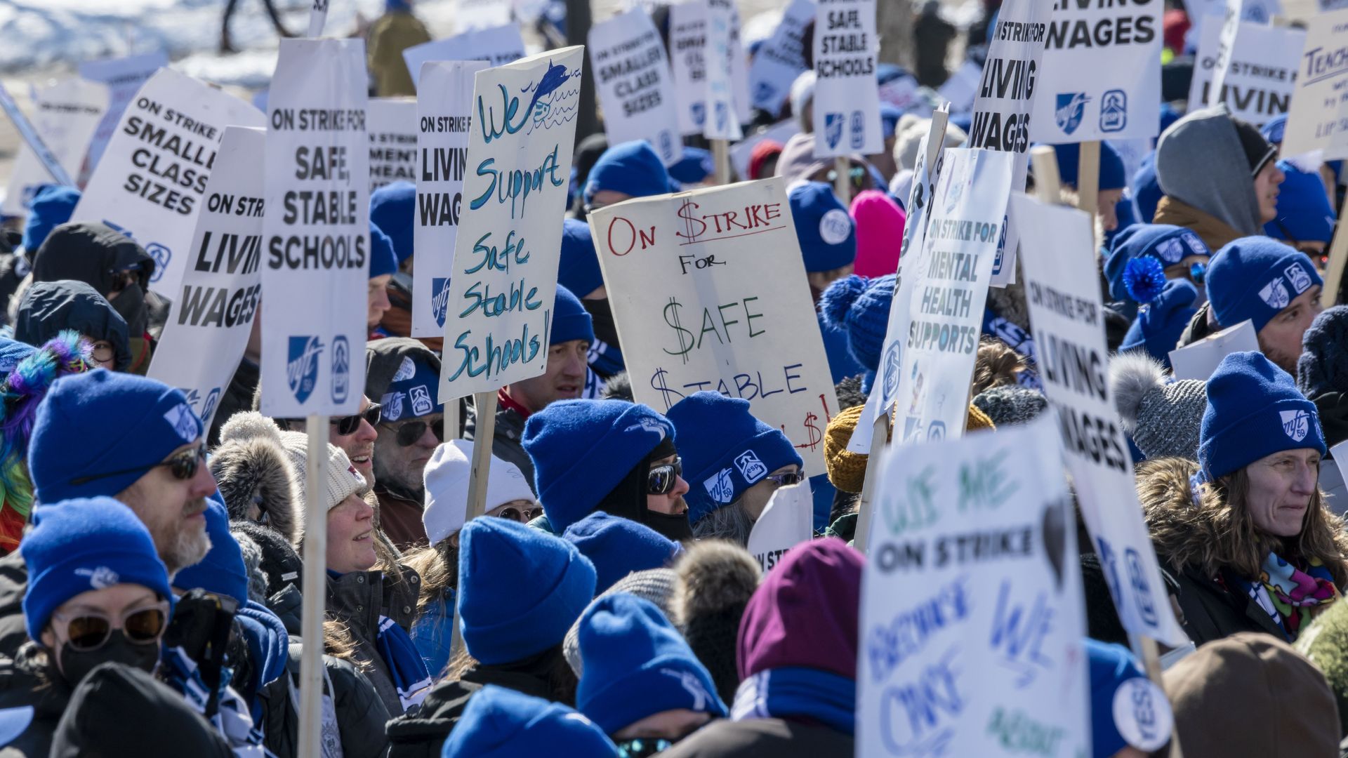 A group of teachers holding picket signs with slogans regarding safety in schools. 