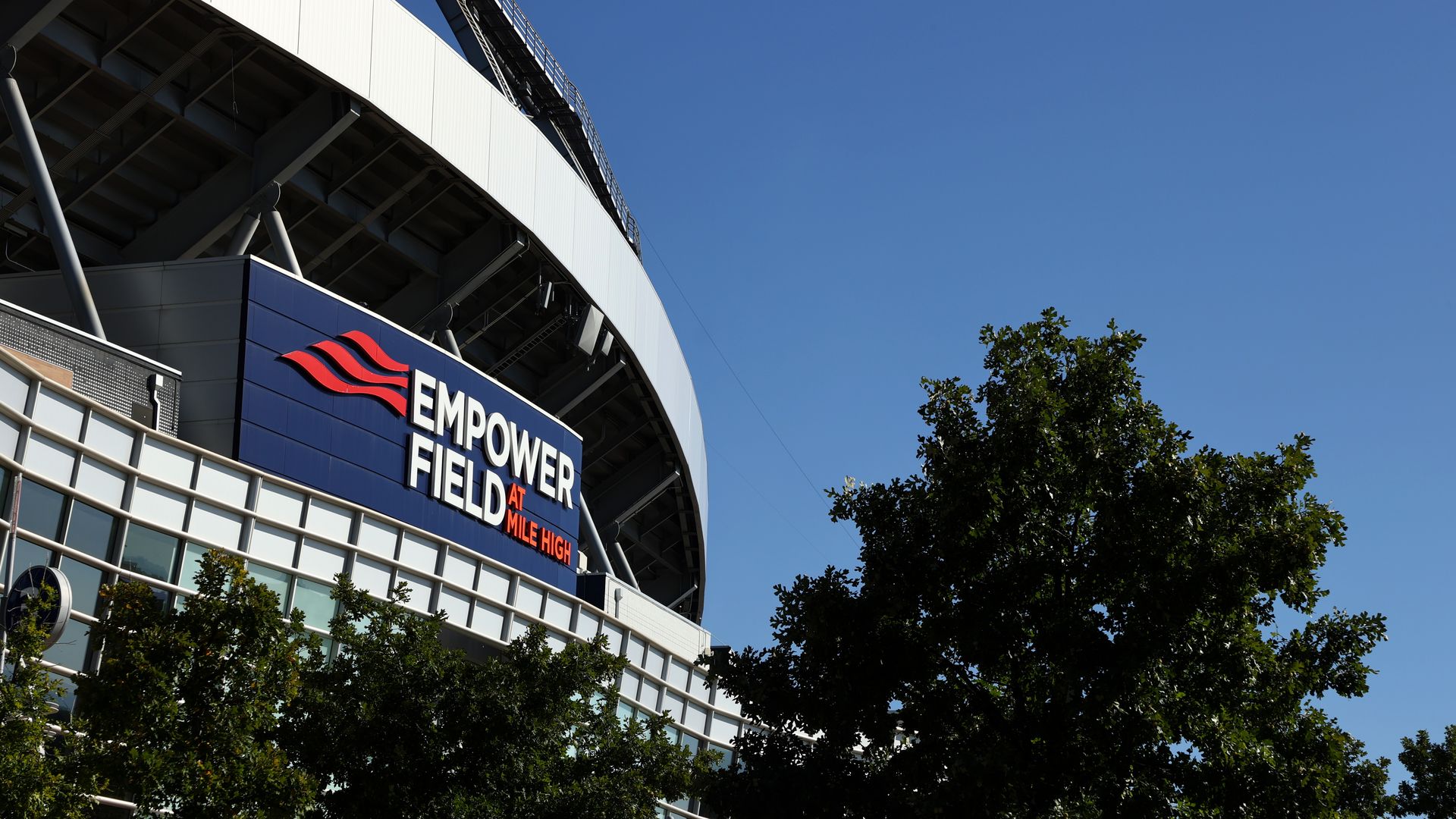 The outside of a sports stadium, with the words EMPOWER FIELD AT MILE HIGH written in white and orange lettering. 