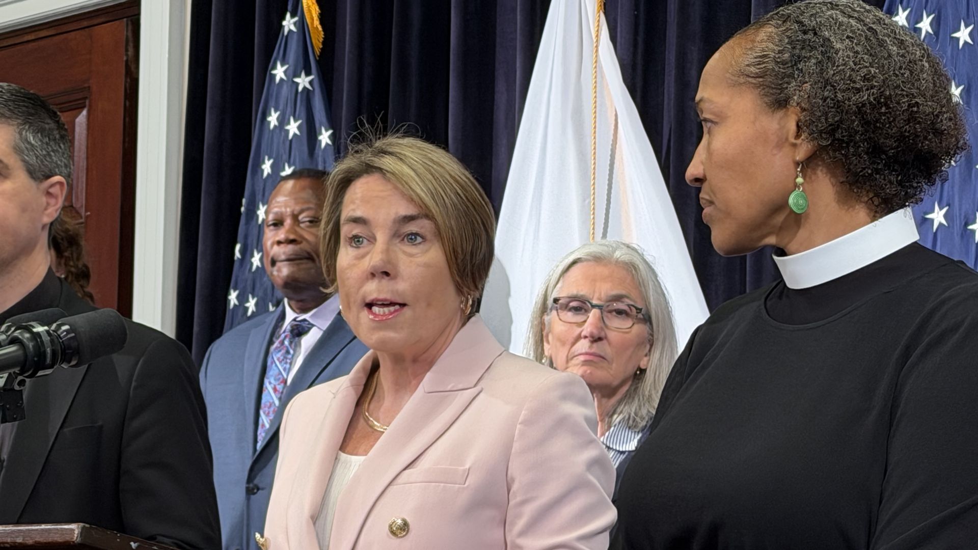 Gov. Maura Healey, center, speaks from a lectern in the Massachusetts State House surrounded by Pastor Dieufort "Keke" Fleurissaint, Sen .Cindy Friedman and the Rev. Mariama White-Hammond on May 28, 2026.