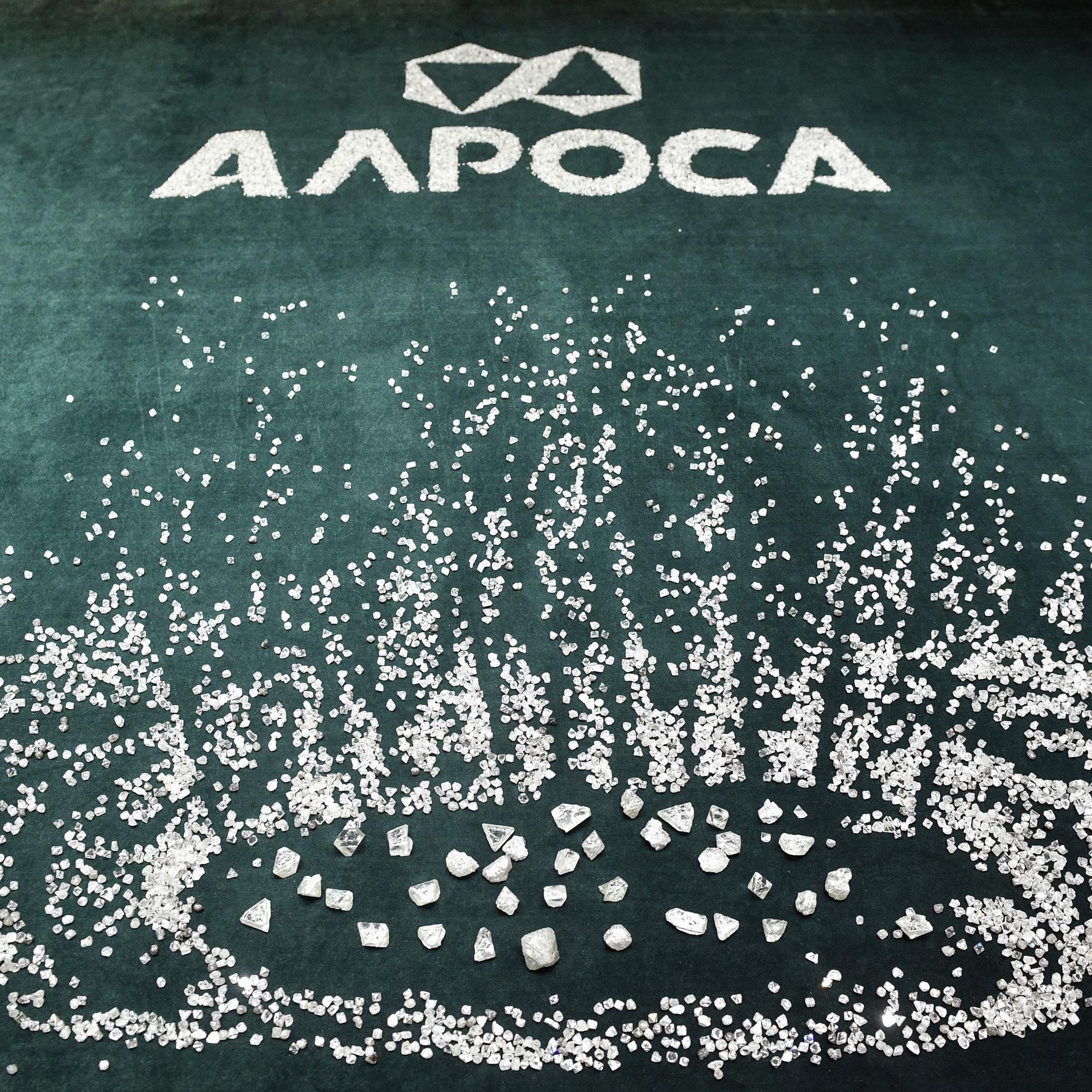 Diamonds scattered on a table under the Alrosa logo