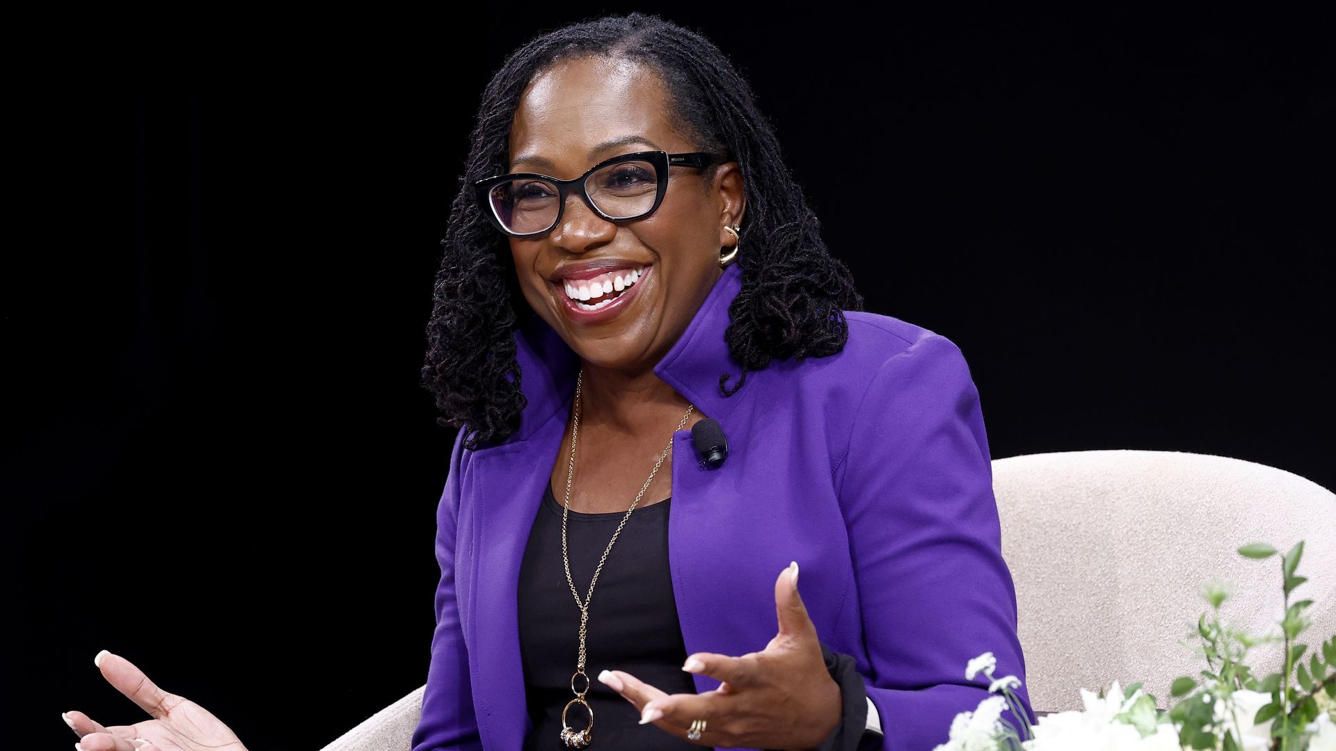 A photo showing Supreme Court justice Ketanji Brown Jackson sitting in a chair and smiling.