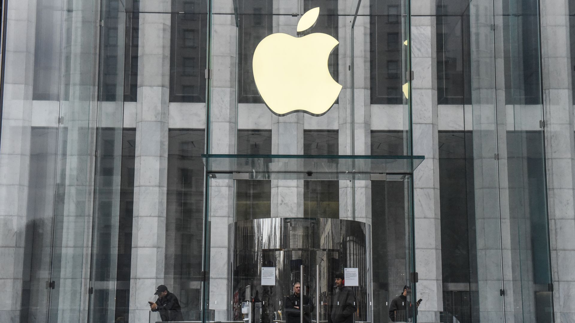 People standing at the entrance of Apple's flagship store in New York City.