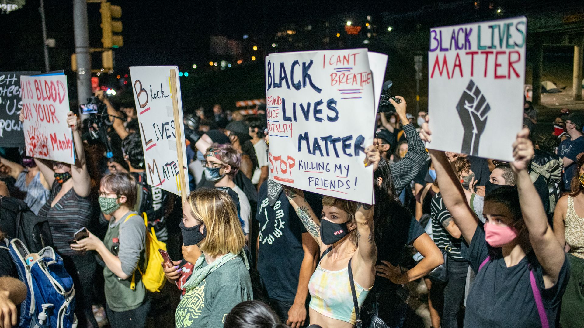 People hold up signs outside Austin Police Department after a vigil for Garrett Foster