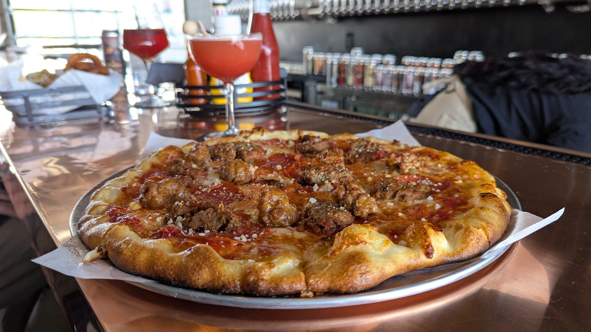 Pizza, a cocktail and a glass of beer on a copper bar