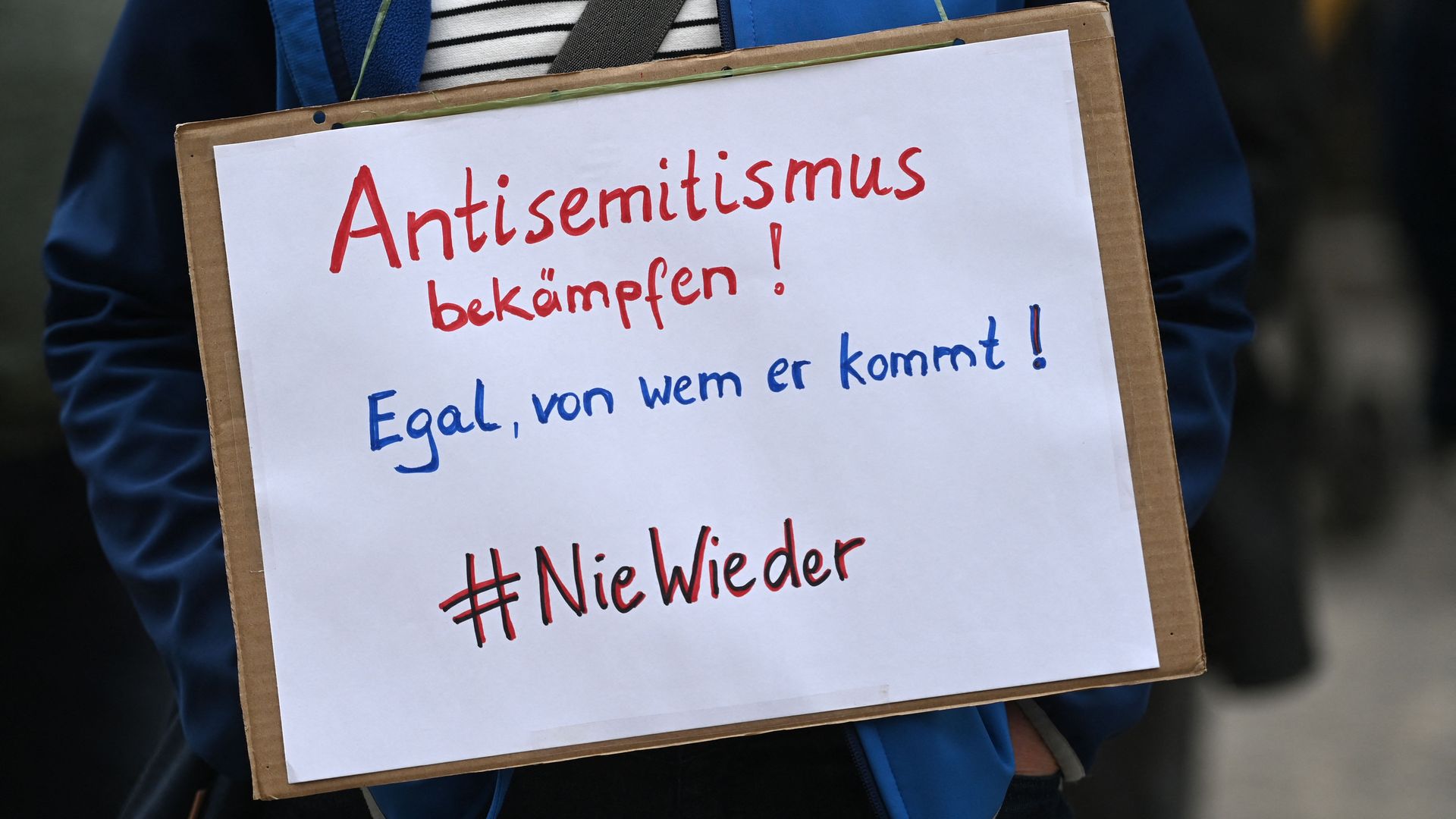 A member of the Initiative against Anti-Semitism Gelsenkirchen holds a placard reading 'fight antisemitism - No matter where it comes from - #never again' during a vigil in front of the synagogue