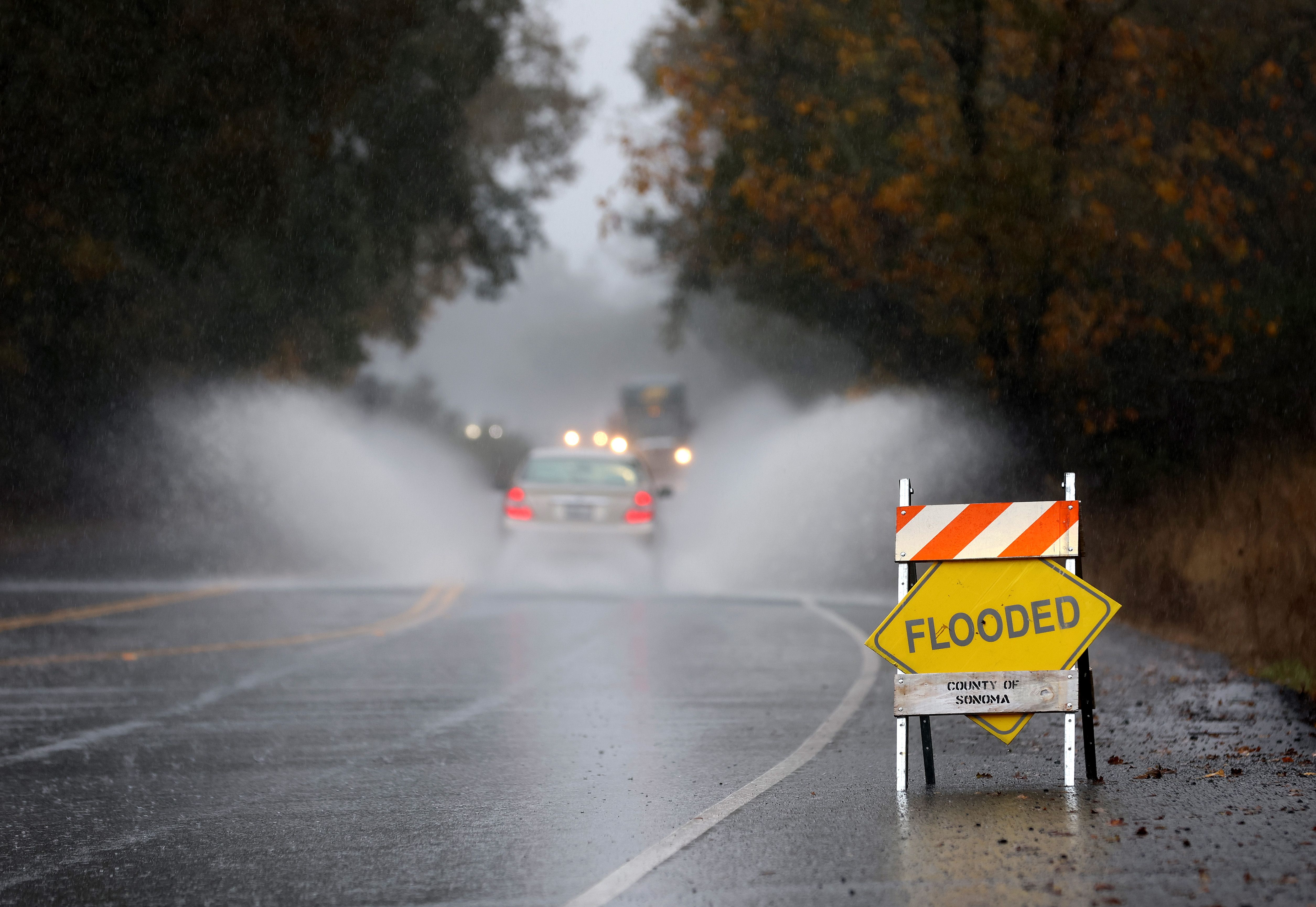 A car kicks up water as it drives through a flooded section of road on November 21, 2024, in Windsor, California. An atmospheric river is bringing heavy rains and wind to the San Francisco Bay Area for a second day and is expected to rain through the weekend. 