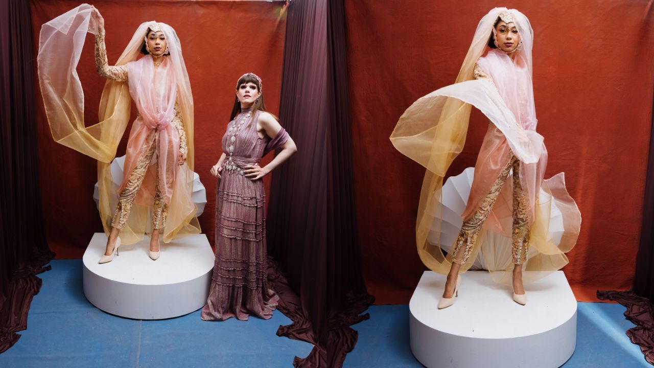 Three models pose in a fashion display: two on white circular platforms wear peach sheer gowns with long veils, while a third in a mauve beaded gown stands between them against a red backdrop.
