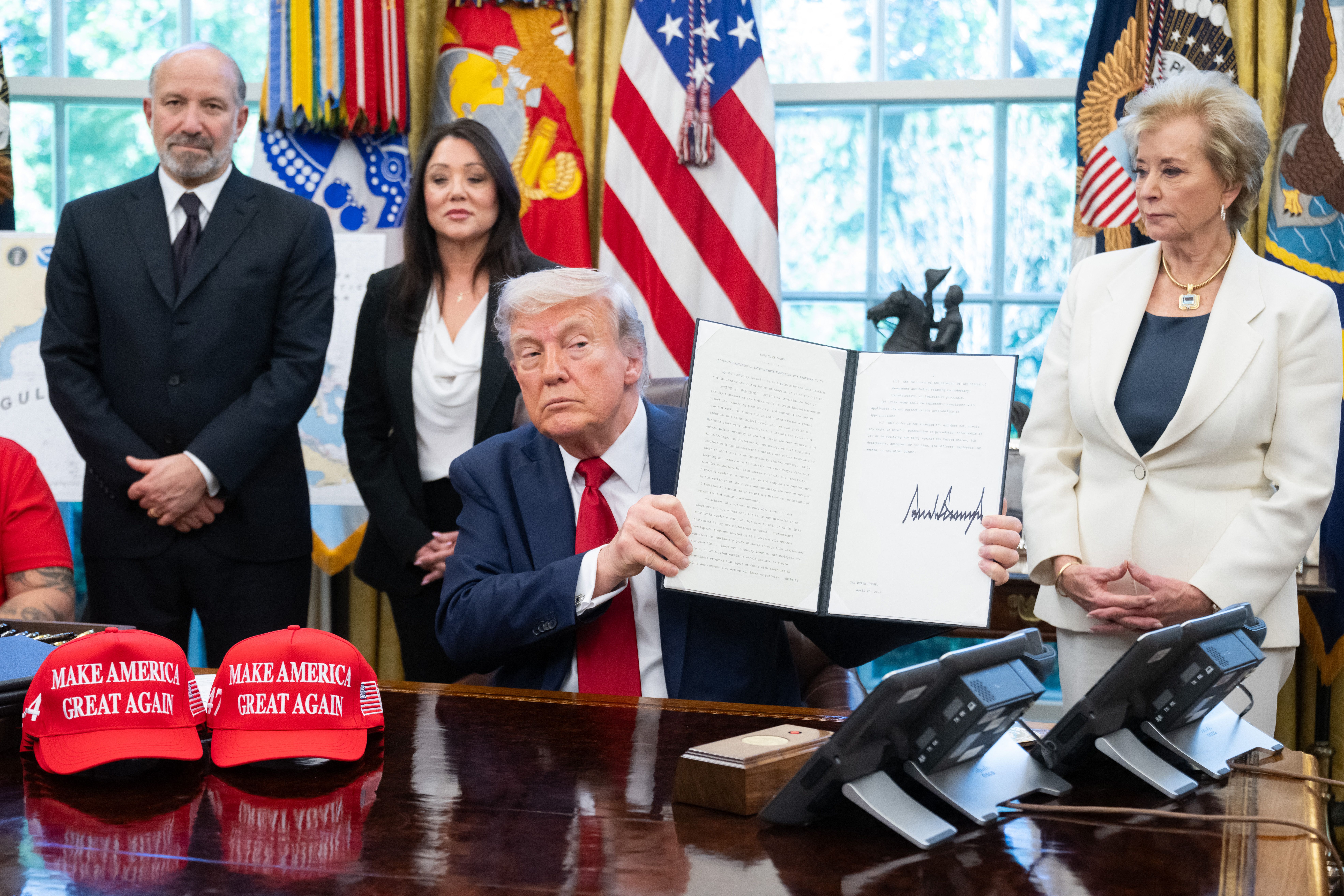 US President Donald Trump signs executive orders relating to higher education institutions, alongside US Secretary of Commerce Howard Lutnick (L) and US Secretary of Education Linda McMahon (R), in the Oval Office of the White House in Washington, DC, on April 23, 2025. (Photo by SAUL LOEB / AFP) (P