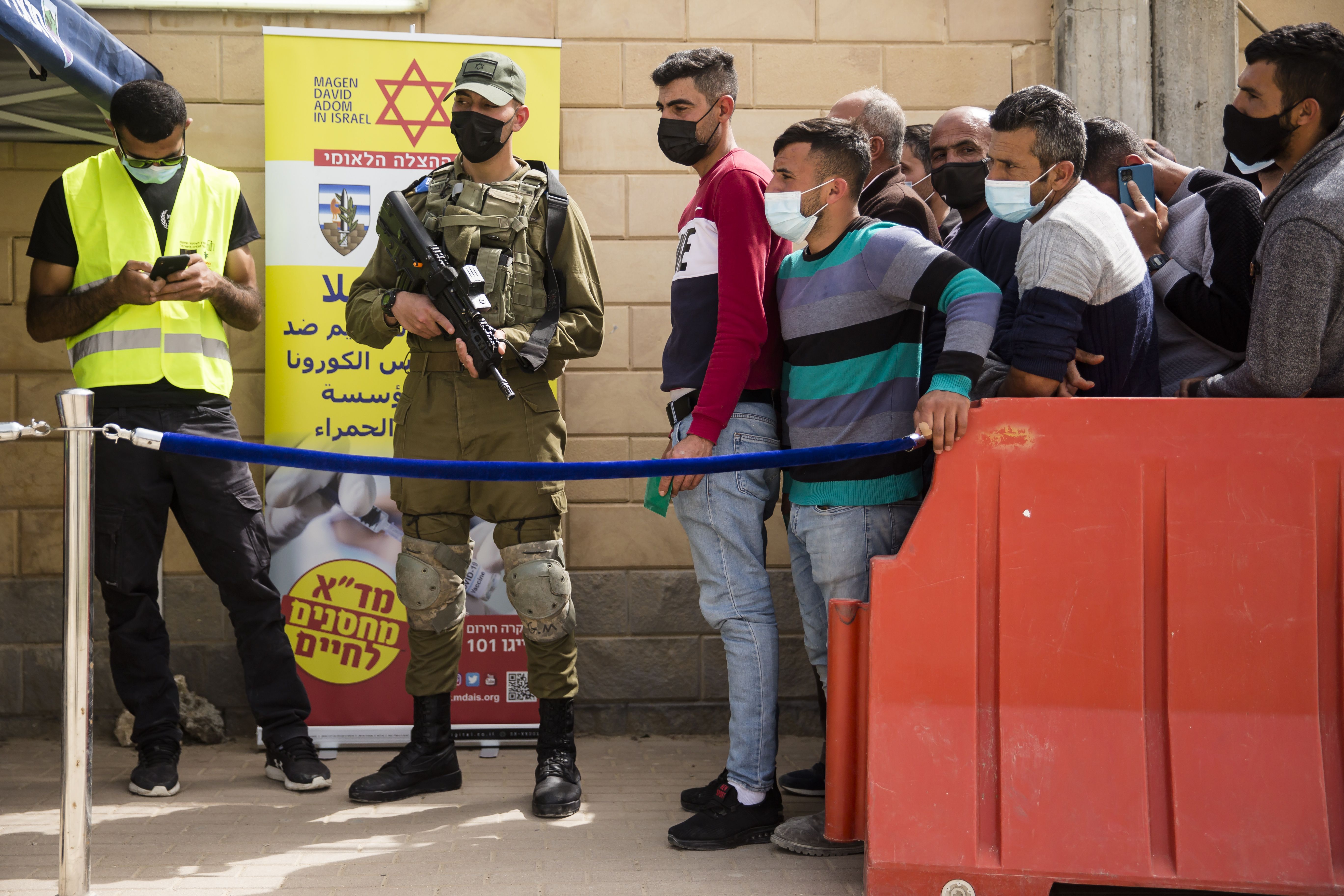 Palestinians who work in Israel wait to receive a Covid-19 vaccine by Israeli medical workers in Meitar crossing checkpoint between the West bank and Israel on March 9
