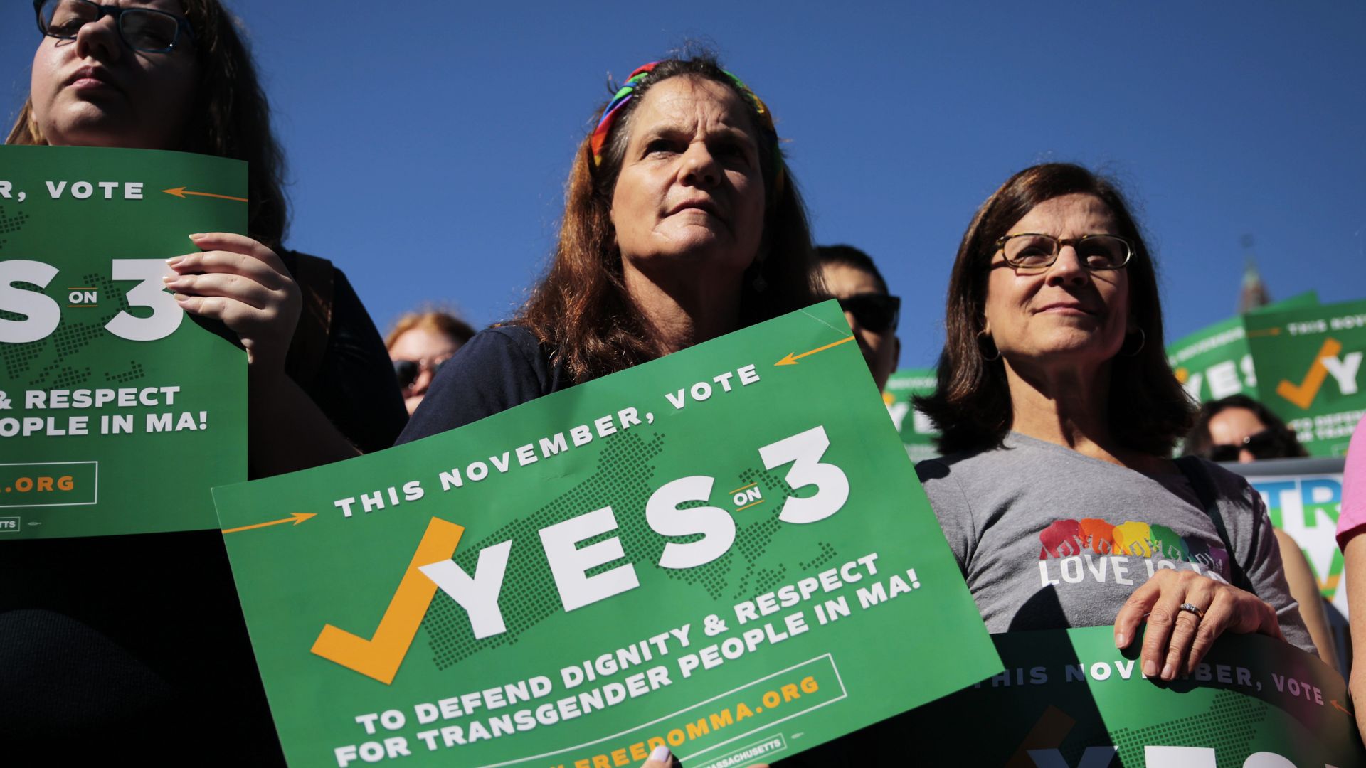 Women hold up signs that say "Yes on 3"