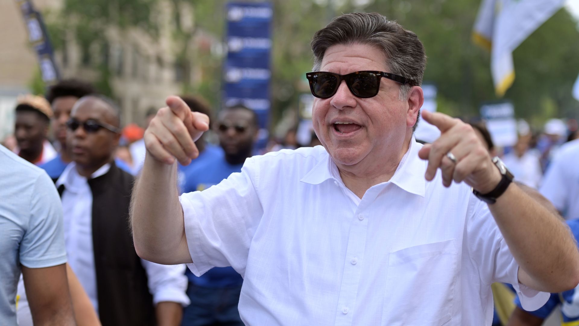 Illinois Gov. JB Pritzker points with both hands while walking in a parade