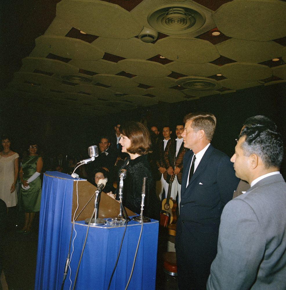 First Lady Jacqueline Kennedy delivers remarks in Spanish during a gala held by the League of United Latin American Citizens at the Rice Hotel in Houston, on Nov. 21, 1963. President John F. Kennedy stands at right and is assassinated the next day in Dallas.